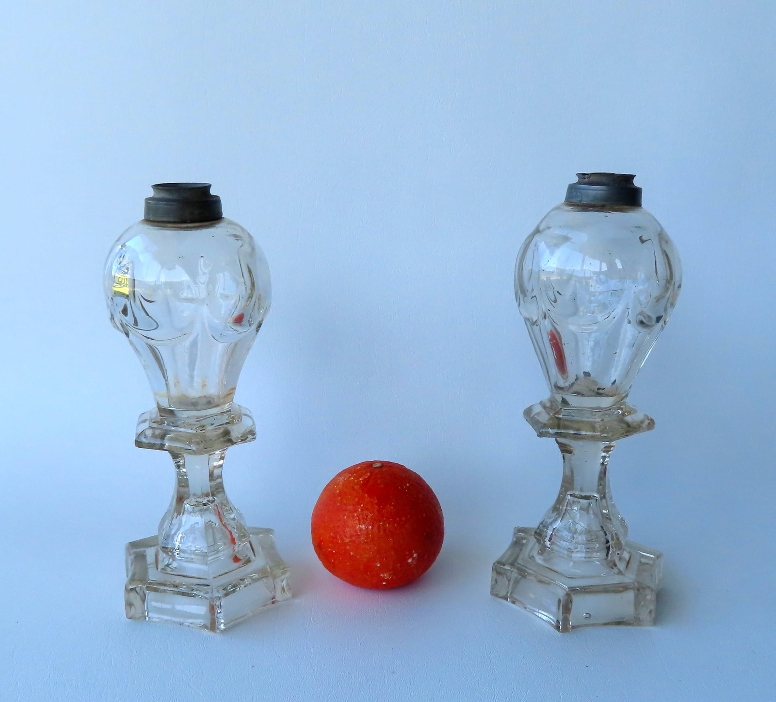 A matched pair of early glass whale oil lamps with glass wafer between reservoir and plinth, early: A matched pair of early glass whale oil lamps with glass wafer between reservoir and plinth, early to mid 19th century, both in very good condition. Measures 9"H.