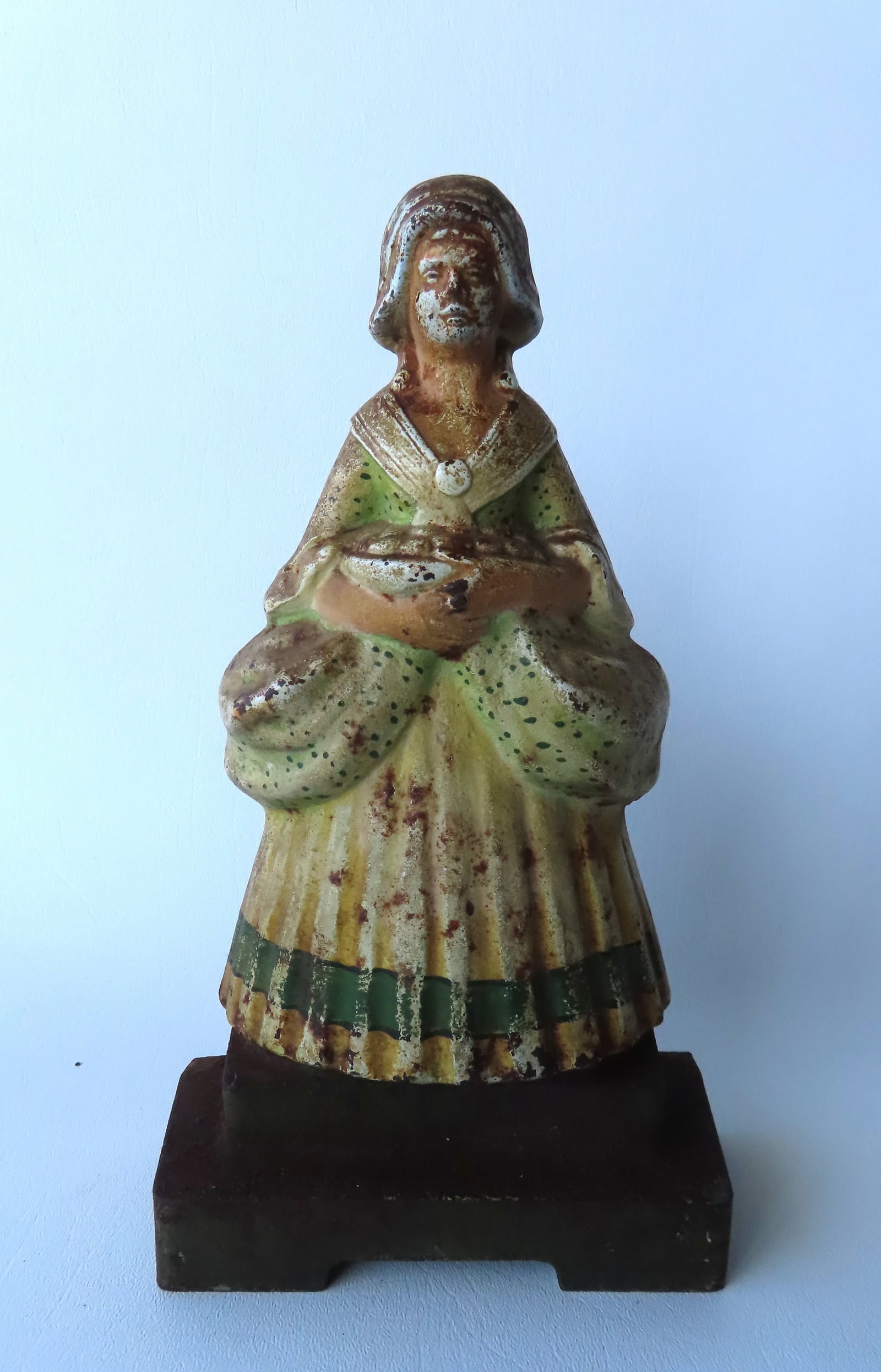 A cast iron door stop, country girl holding a bowl of goodies, probably fruit. Early 20th century.: A cast iron door stop, country girl holding a bowl of goodies, probably fruit. Early 20th century. 10 1/4"H x 6"W. Original paint and in good condition.