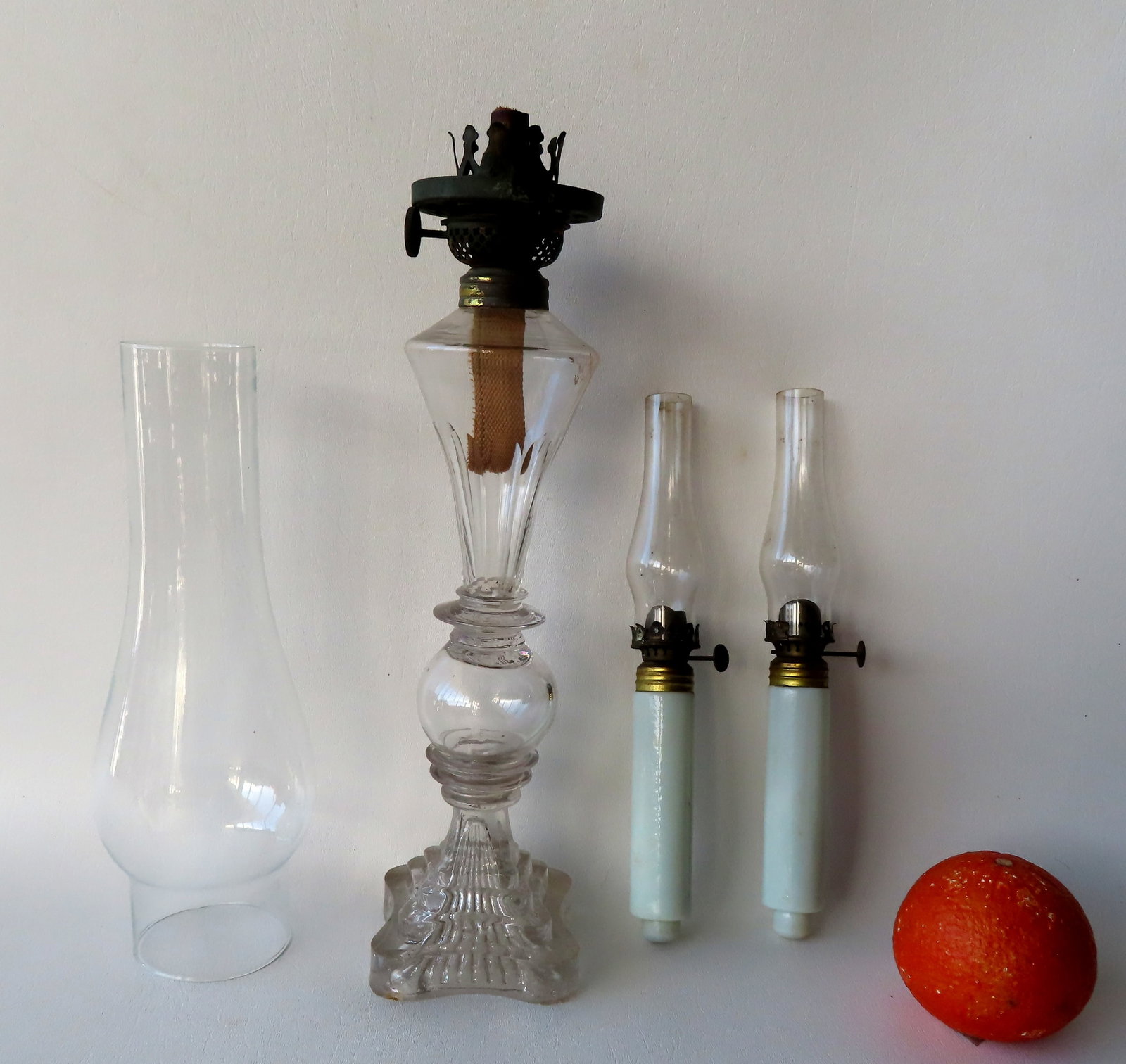 Three early glass lighting devices including: A colorless Sandwich glass whale oil lamp on stepped: Three early glass lighting devices including: A colorless Sandwich glass whale oil lamp on stepped base - 3 sections separated by glass wafers - burner is 19th century but possibly not original and mi