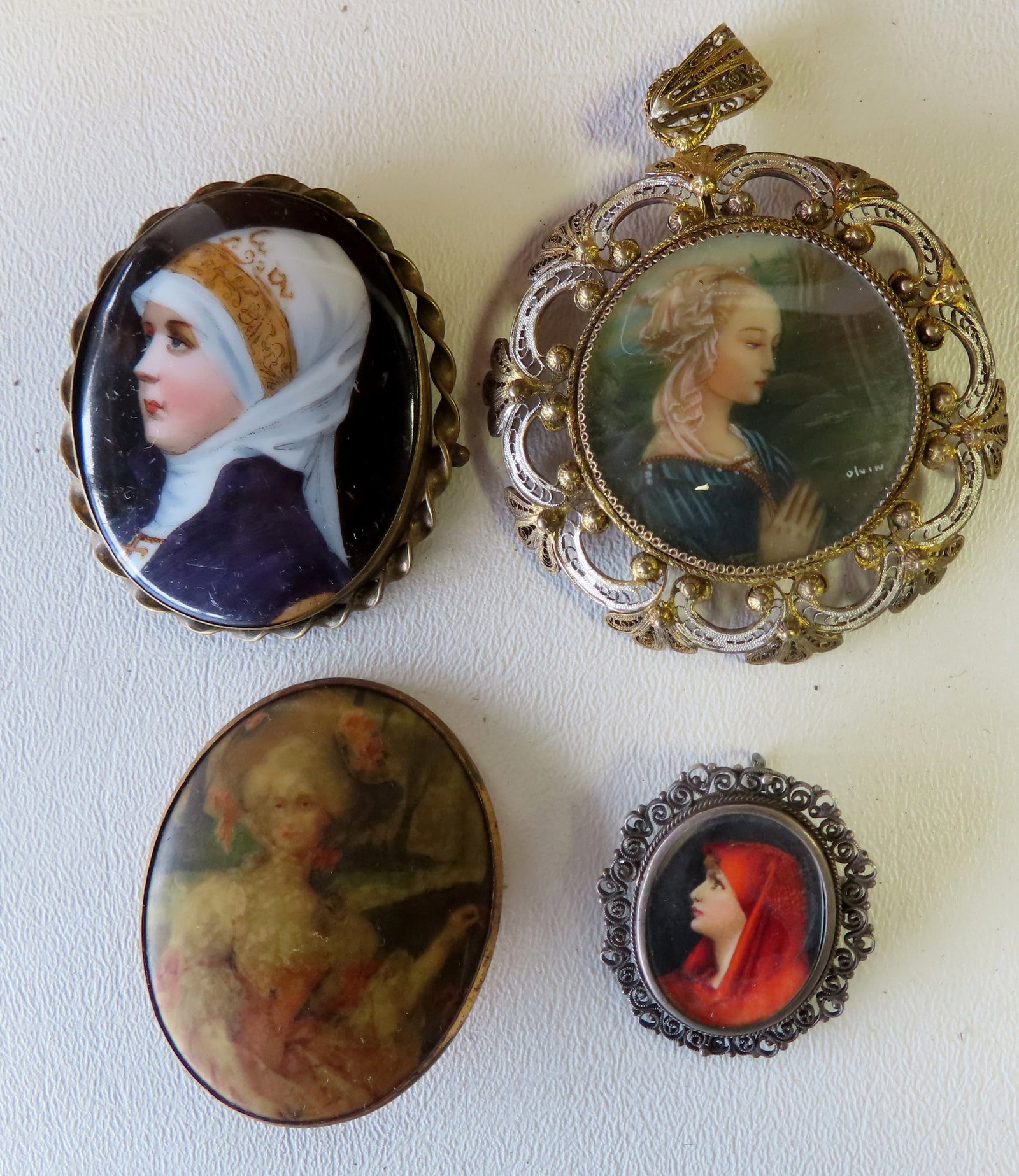 Four hand painted miniature portraits including: Pendant of a lady with red veil housed in an 800: Four hand painted miniature portraits including: Pendant of a lady with red veil housed in an 800 silver case with filigree border, 19th century - 1 1/4" x 1 1/2" - very good condition; pendant depict