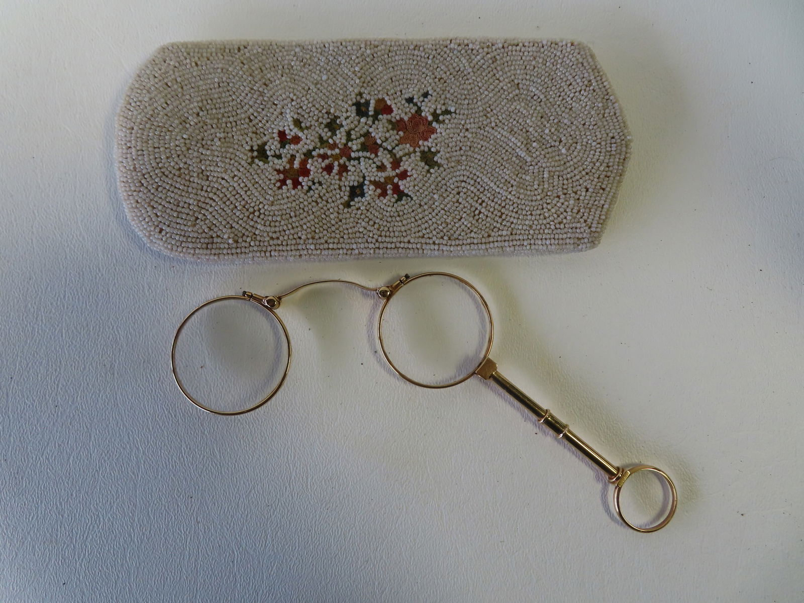 A pair of 14k gold eye glasses with attached handle. Marked 14k on underside of nose guard. Very: A pair of 14k gold eye glasses with attached handle. Marked 14k on underside of nose guard. Very good condition. Sold with eye glass case marked "Made in France" (some losses to the tiny pearls). Tota