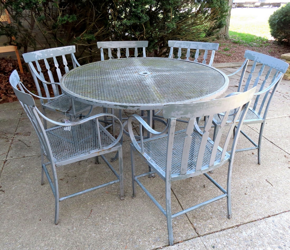 A custom made wrought iron patio set consisting of a 48" round table with wire mesh top, mounted on: A custom made wrought iron patio set consisting of a 48" round table with wire mesh top, mounted on a circular pedestal base, with 6 matching arm chairs also with mesh seats and back and 2 matching en
