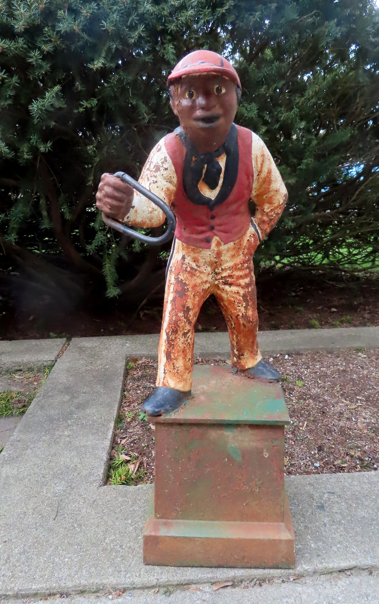 A vintage cast iron lawn jockey mounted on original cast iron base, late 19th to early 20th century.: A vintage cast iron lawn jockey mounted on original cast iron base, late 19th to early 20th century. Appears to retain some of its original paint, some surface rust, else good condition. Measures 35"H