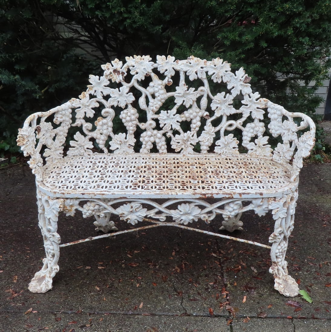 A good cast iron garden settee in the grape and vine pattern, heavy and detailed construction with: A good cast iron garden settee in the grape and vine pattern, heavy and detailed construction with original cross stretchers, signed "Atlanta Stove Works" (active 1898-1957). Layers of old paint, mino