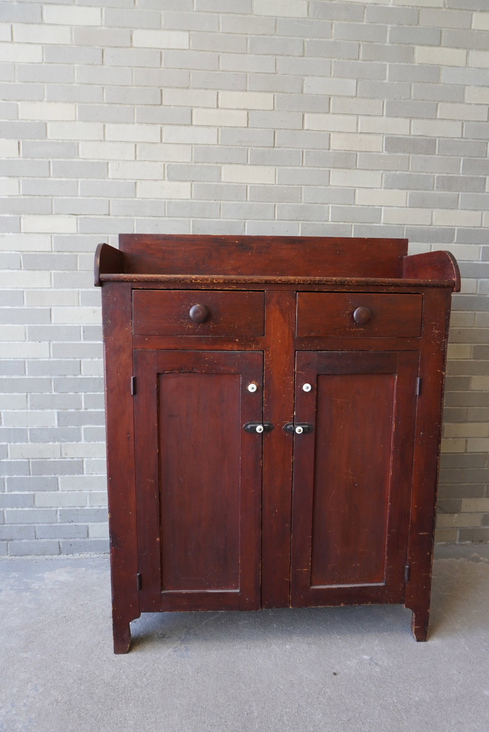 Pine Jelly cupboard having a backsplash and 2 short drawers with porcelain pulls over 2 paneled: Pine Jelly cupboard having a backsplash and 2 short drawers with porcelain pulls over 2 paneled doors with porcelain pulls and porcelain and iron latch and mounted on cutout base. The hardware is all 