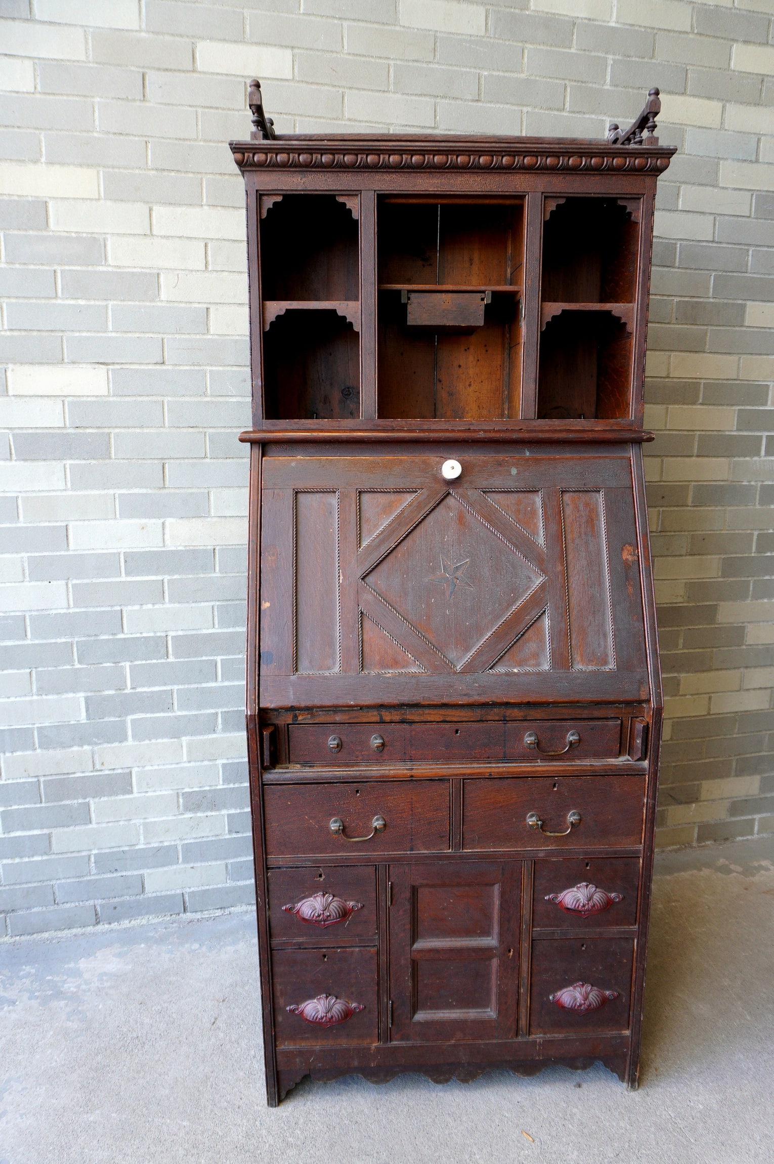 A folk-art secretary desk having an open top with gallery, pigeon holes, and single drawer, over a: A folk-art secretary desk having an open top with gallery, pigeon holes, and single drawer, over a drop front desk with inlaid star in the center of the paneled lid, over 1 long drawer, over 2 short d