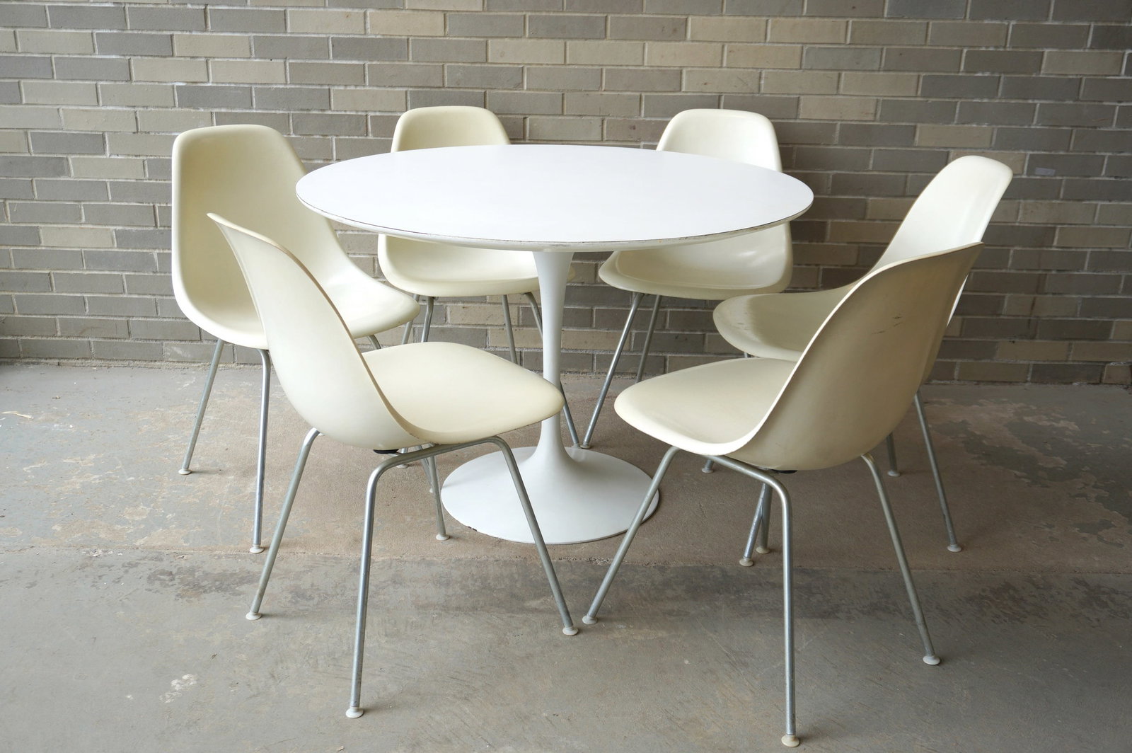 An original mid-century modern tulip table and 6 signed Herman Miller molded fiberglass chairs. The: An original mid-century modern tulip table and 6 signed Herman Miller molded fiberglass chairs. The table with a heavy cast iron base in original white paint with some touchup on base, and measures 42