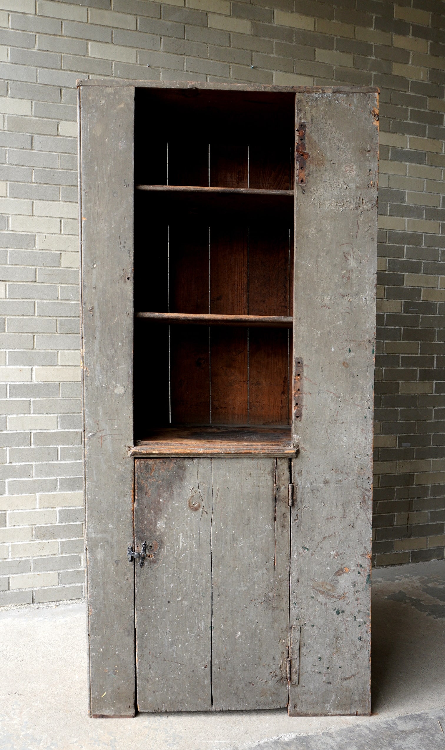 An early narrow kitchen cupboard in old gray-green paint, possibly original, having an open top over: An early narrow kitchen cupboard in old gray-green paint, possibly original, having an open top over 1 door. Originally had a door on the top section which is missing - likely was built in at one time
