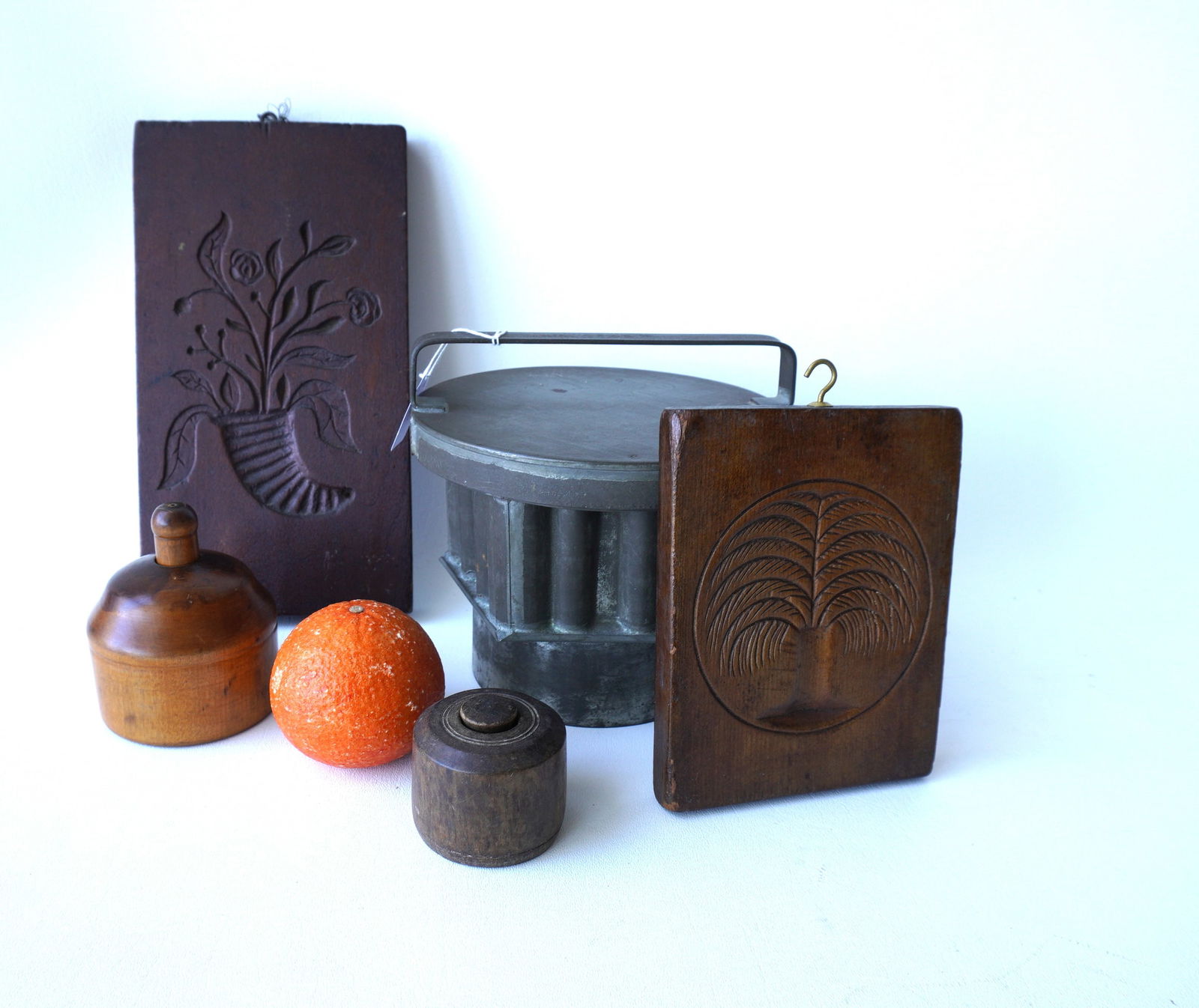 Grouping of 4 wooden molds and a tin pudding or jello mold. Includes 2 hand carved wooden maple: Grouping of 4 wooden molds and a tin pudding or jello mold. Includes 2 hand carved wooden maple syrup molds, floral patterns, early to mid 19th century - the largest measures 5 7/8"W x 10 3/4"H; 2 but