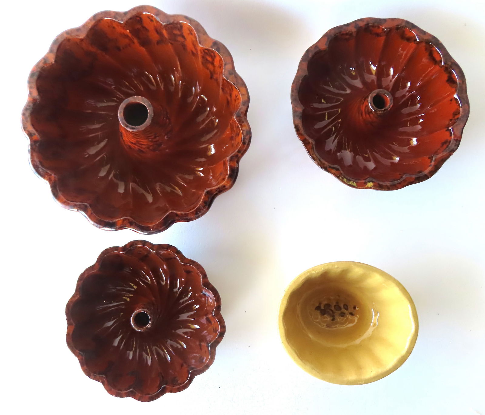 Three redware turk molds with manganese decorations in graduated sizes, together with a yellowware: Three redware turk molds with manganese decorations in graduated sizes, together with a yellowware Jello mold (chip on edge of base) - all mid 19th century. The turk molds all with slight rim wear, bu