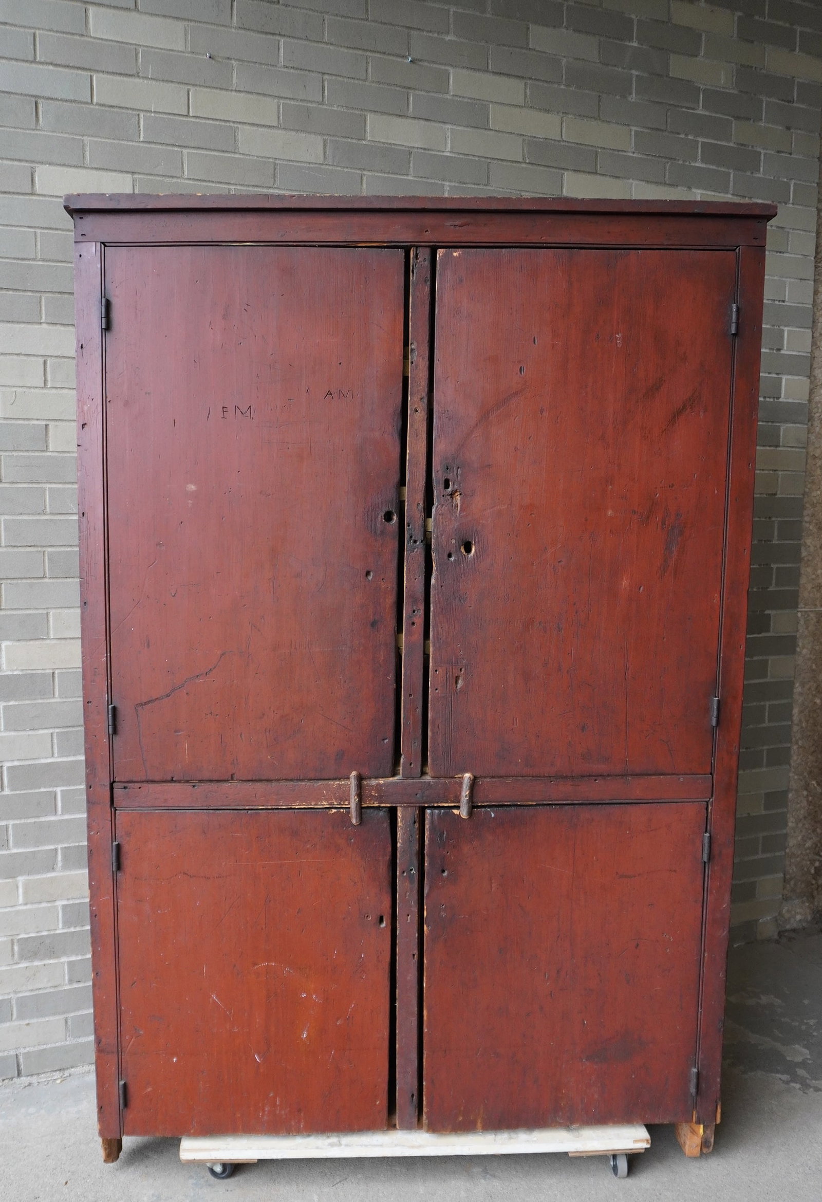 A primitive Hudson Valley 4 door cupboard in old red paint having 2 doors over 2 doors each: A primitive Hudson Valley 4 door cupboard in old red paint having 2 doors over 2 doors each constructed of 1 board, mounted on cutout base. One back leg with repair and 1 front leg with newer brace, m