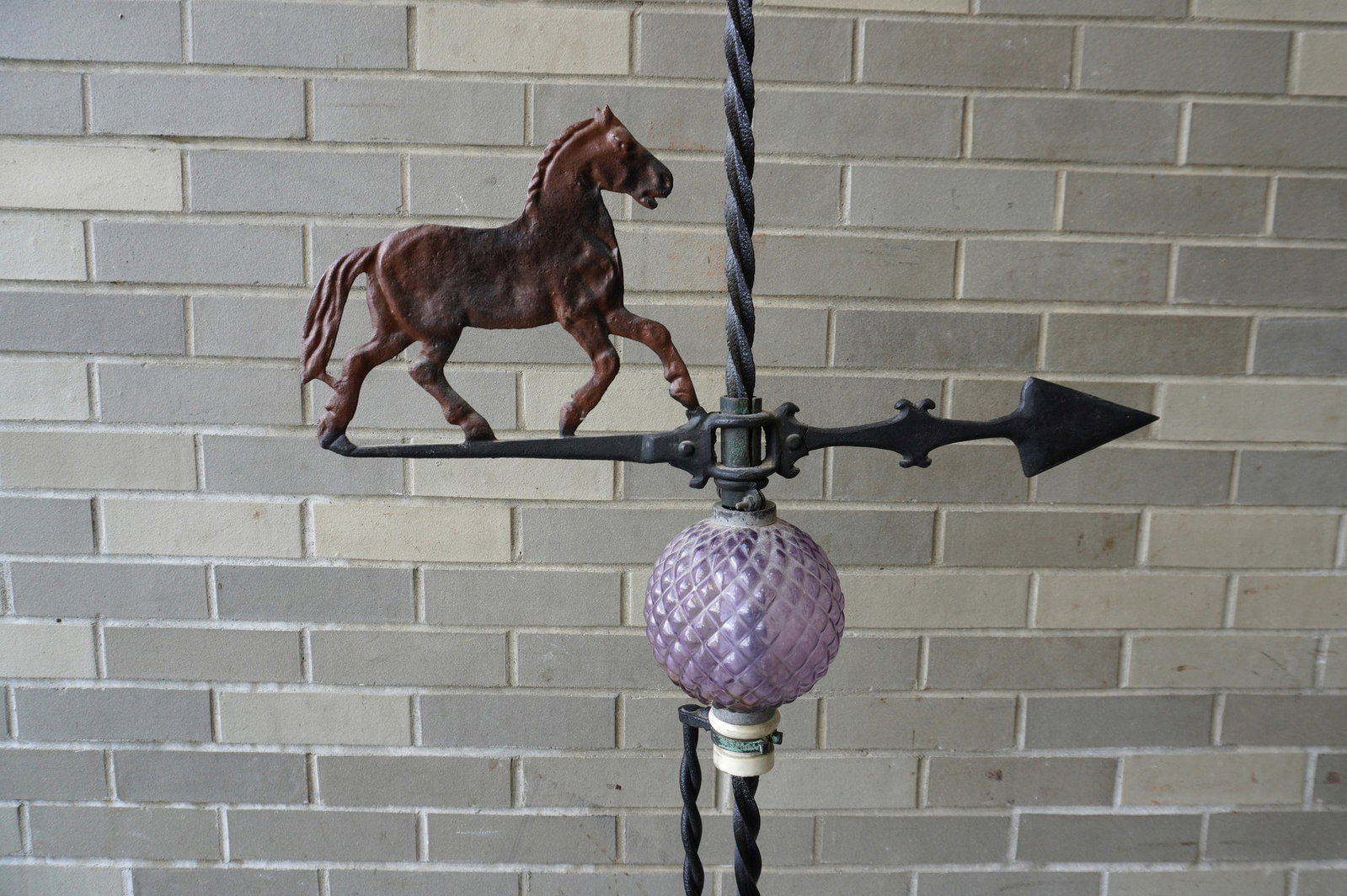 A lightening rod with metal horse on arrow above amethyst glass ball above porcelain mount attached: A lightening rod with metal horse on arrow above amethyst glass ball above porcelain mount attached to original iron stand (repainted in black paint) - the spear shape finial signed "Franklin B E R" -