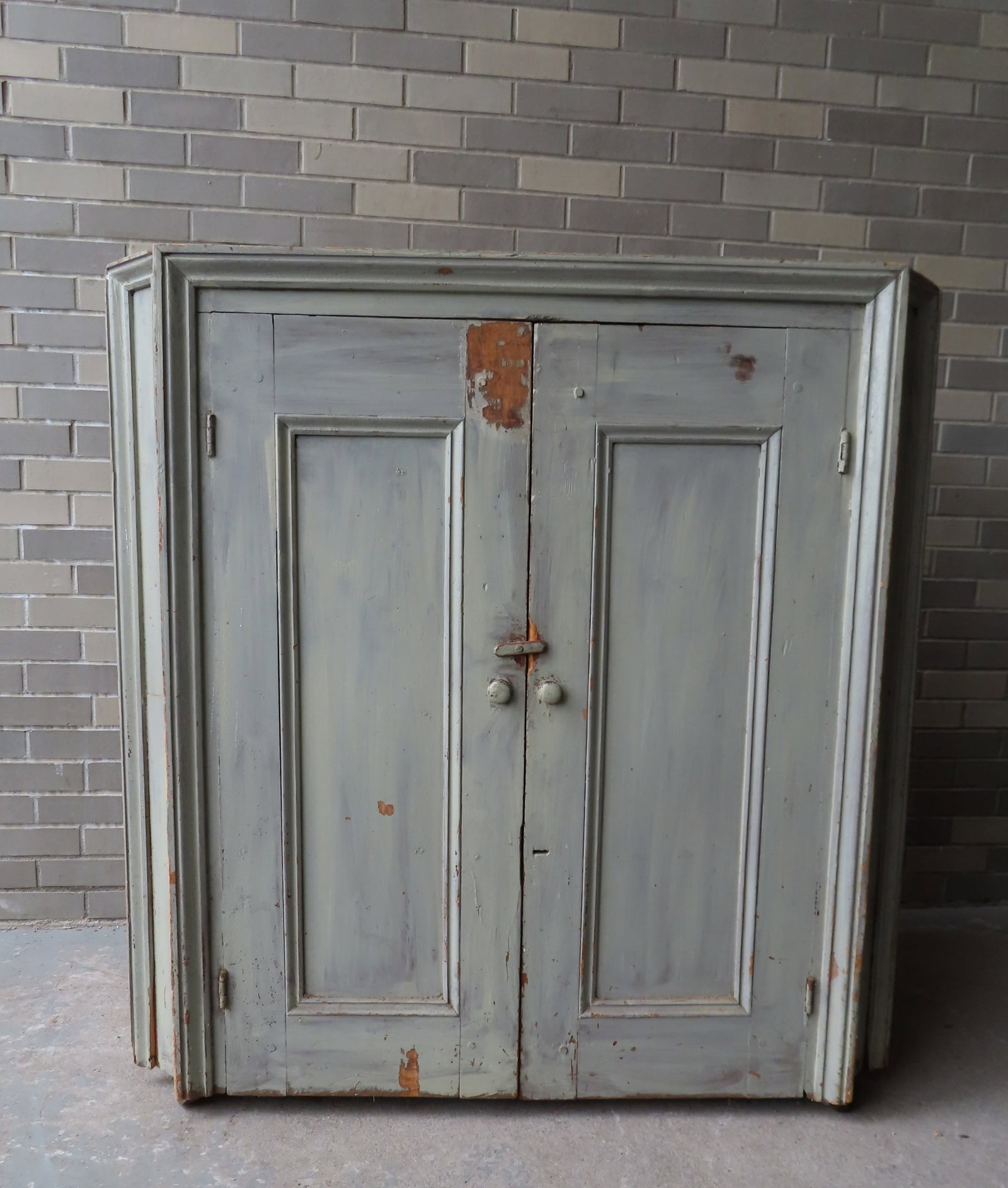 A floor standing primitive corner cupboard with picture frame molding, in old mint-green wash paint,: A floor standing primitive corner cupboard with picture frame molding, in old mint-green wash paint, having 2 paneled doors, mounted on casters, mid 19th century, square nail construction - probably t