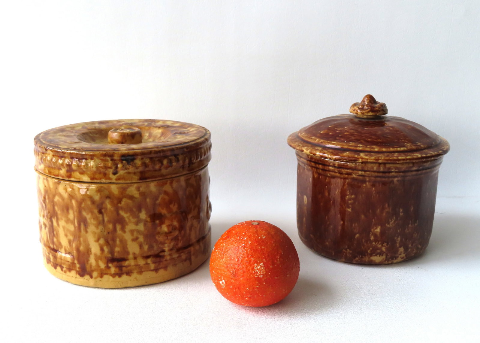 Two Bennington covered spongeware sugar bowls. The first decorated with embossed exotic birds,: Two Bennington covered spongeware sugar bowls. The first decorated with embossed exotic birds, trees, and a fence border - the lid with beaded edge and floral embossed lid - some crazing but overall v