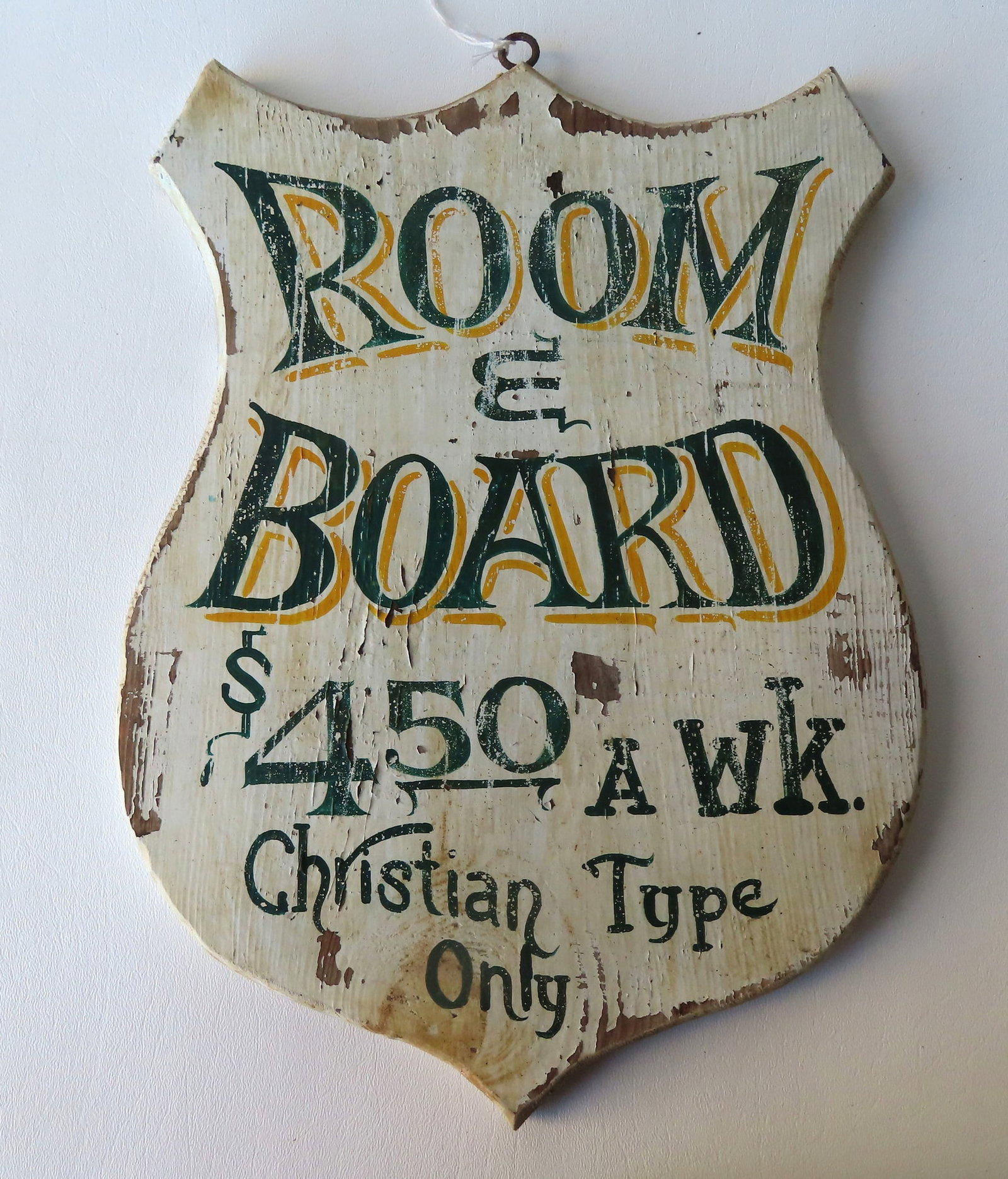 A shield shaped wooden sign "ROOM & BOARD / $4.50 A WK. / Christian Type Only", probably early 20th: A shield shaped wooden sign "ROOM & BOARD / $4.50 A WK. / Christian Type Only", probably early 20th century - note the cross-cut saw marks on reverse of board. Some paint loss and flaking, but overall