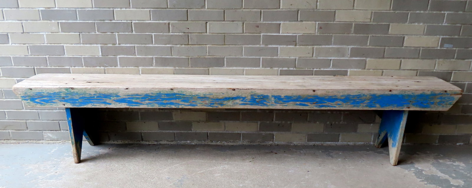 A primitive pine bench with side braces and bootjack ends, traces of original blue paint on base -: A primitive pine bench with side braces and bootjack ends, traces of original blue paint on base - top is weathered - structurally sound and very sturdy. Mid 19th century. Measures 94"L x 13 1/2"D x 1