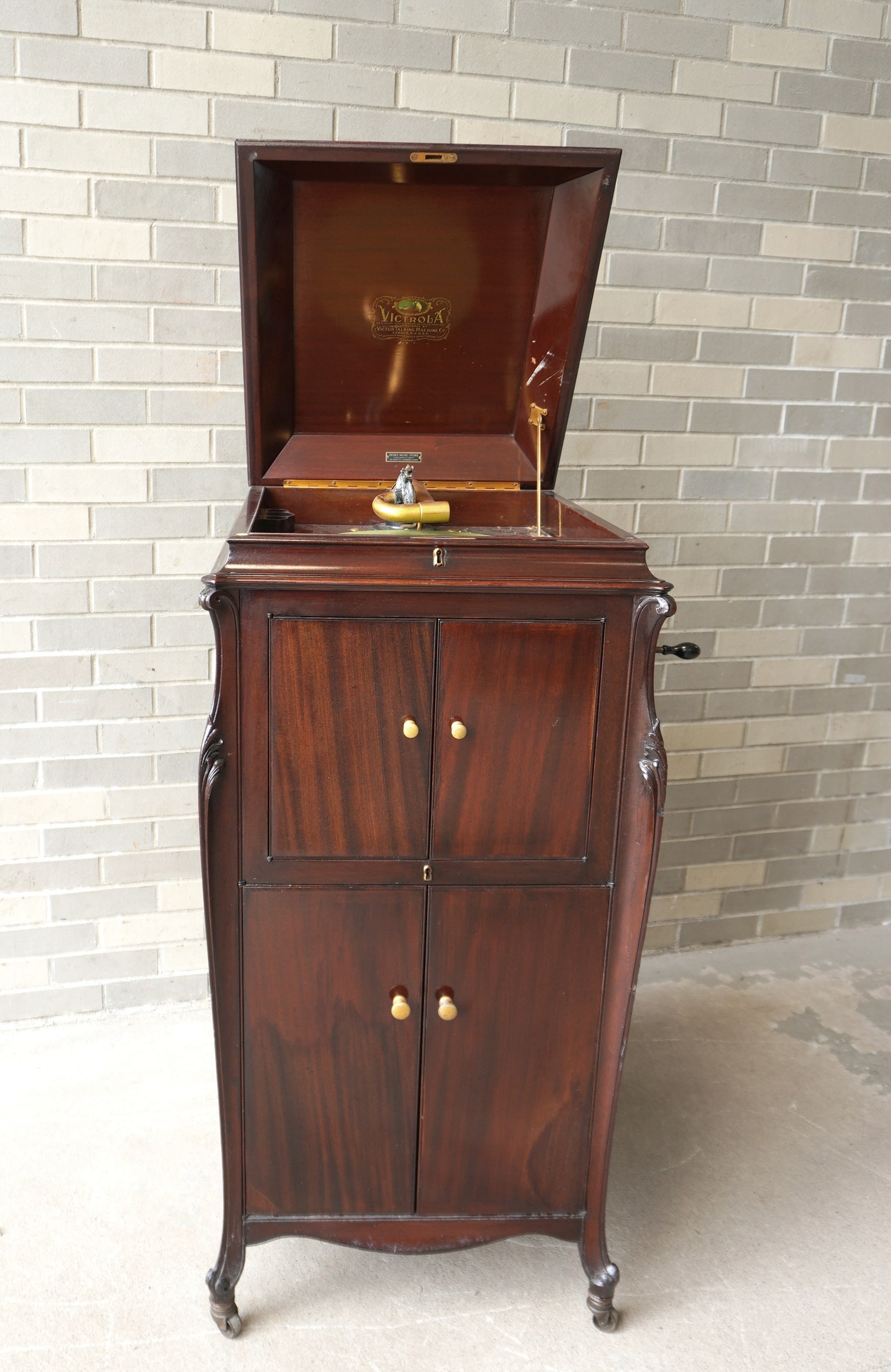 A mahogany floor standing crank Victrola record player having 2 speaker doors over 2 locked doors: A mahogany floor standing crank Victrola record player having 2 speaker doors over 2 locked doors for holding records. Original Victrola label on interior indicating the unit was manufactured by the V