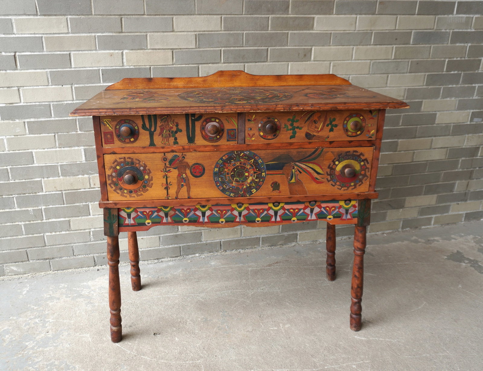 An unusual sideboard with incised and hand painted Native American decorations on the top, front,: An unusual sideboard with incised and hand painted Native American decorations on the top, front, sides and legs, and having 2 short drawers over 1 long drawer, circa 1930-40. Some surface scratches t