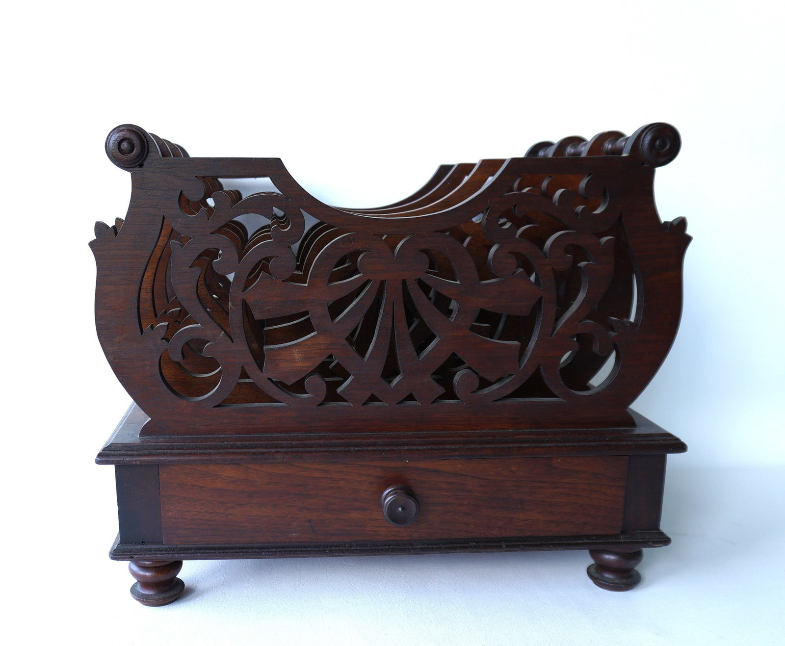 An ornate black walnut magazine rack with carved open work dividers, lower dovetailed drawer, and: An ornate black walnut magazine rack with carved open work dividers, lower dovetailed drawer, and mounted on turned feet, late 19th century. Some use wear but overall good condition. Measures 20"W x 1