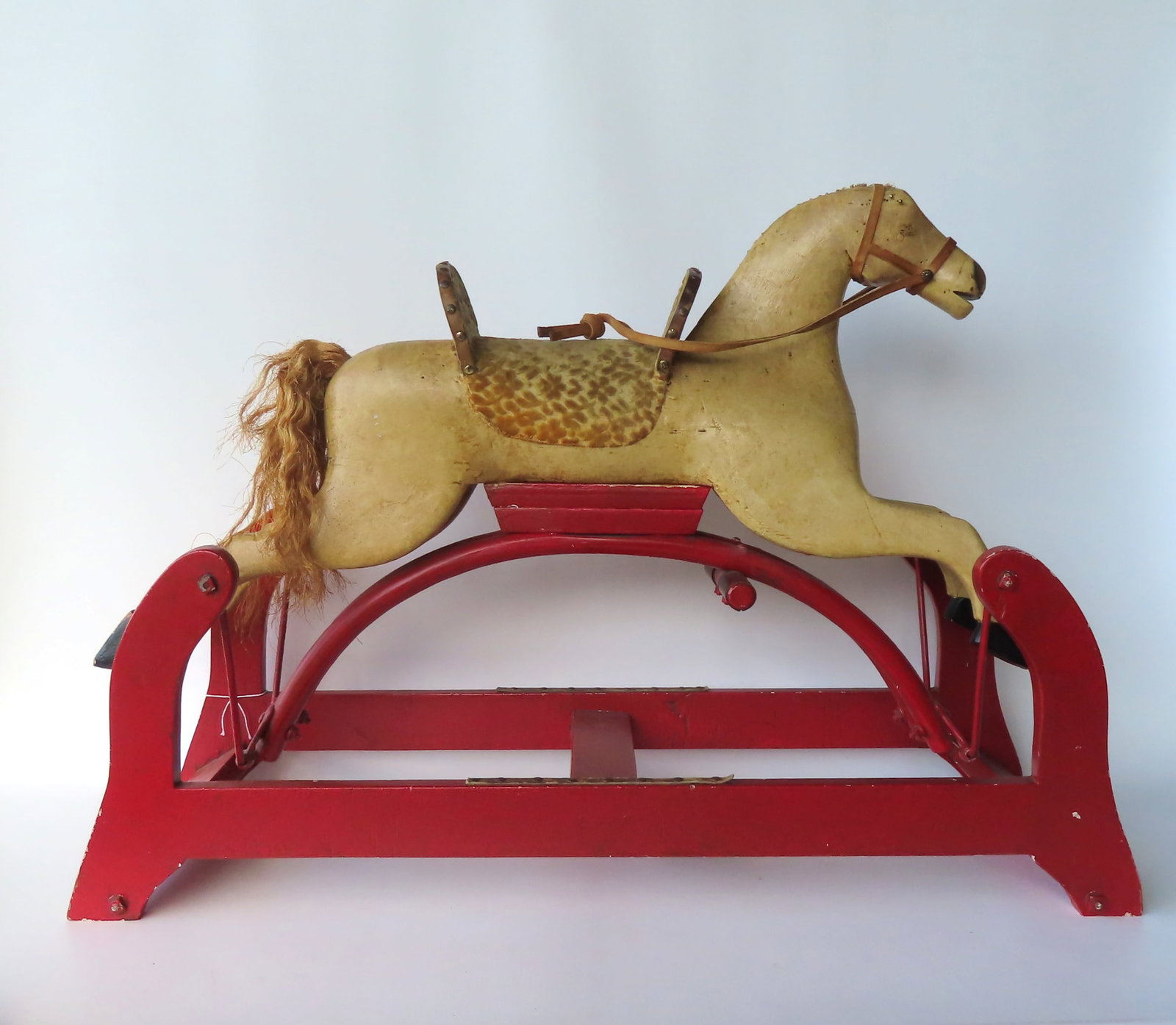 A small size early hobby horse in old paint with original saddle mounted on original platform. All: A small size early hobby horse in old paint with original saddle mounted on original platform. All solid wood hand carved construction. Missing mane, otherwise very good condition. Probably mid to lat