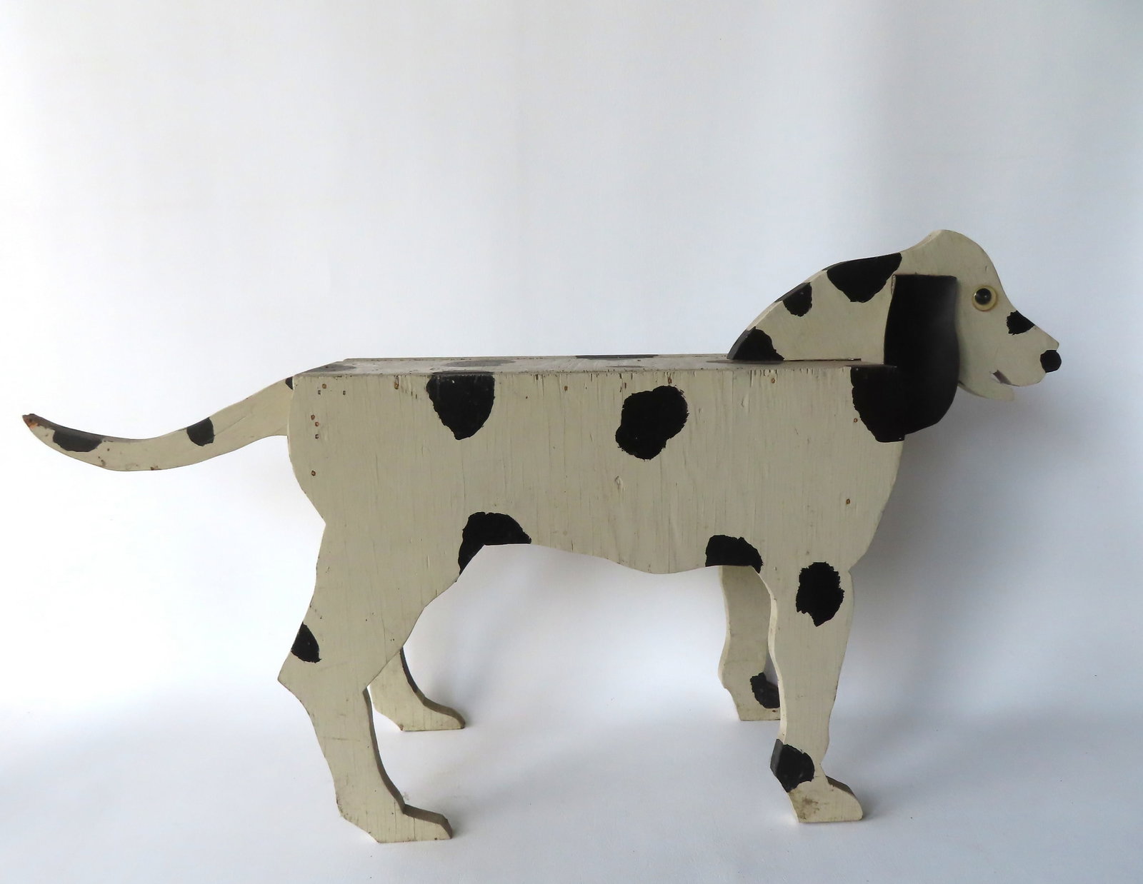 A folk art child's bench in the form of a spotted black and white dog, circa 1970. Custom made in: A folk art child's bench in the form of a spotted black and white dog, circa 1970. Custom made in good condition. Measures 33"L x 7 3/4"W x 18"H.