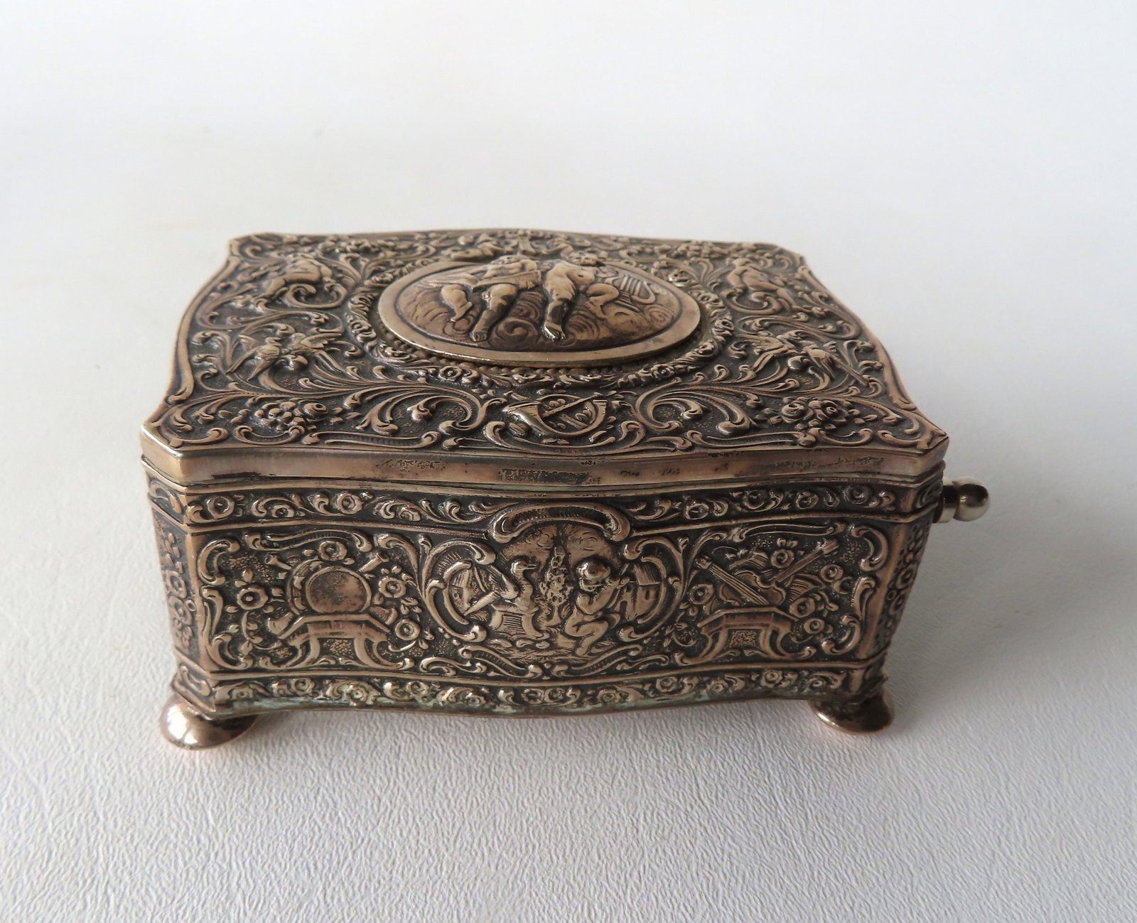 A very fine miniature Sterling Silver automaton singing bird music box, mid to late 19th century.: A very fine miniature Sterling Silver automaton singing bird music box, mid to late 19th century. The entire box profusely decorated in musical theme, with cherubs, birds, flowers on vines, flowers in