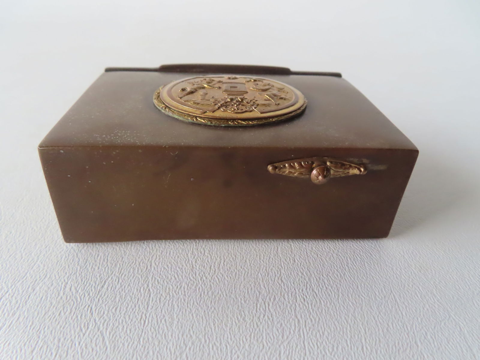 A miniature automaton singing bird music box, the case appears to be brown gutta percha, circa: A miniature automaton singing bird music box, the case appears to be brown gutta percha, circa 1860-80 - note the lift top storage compartment on the back side, likely for holding cigarettes. The feat