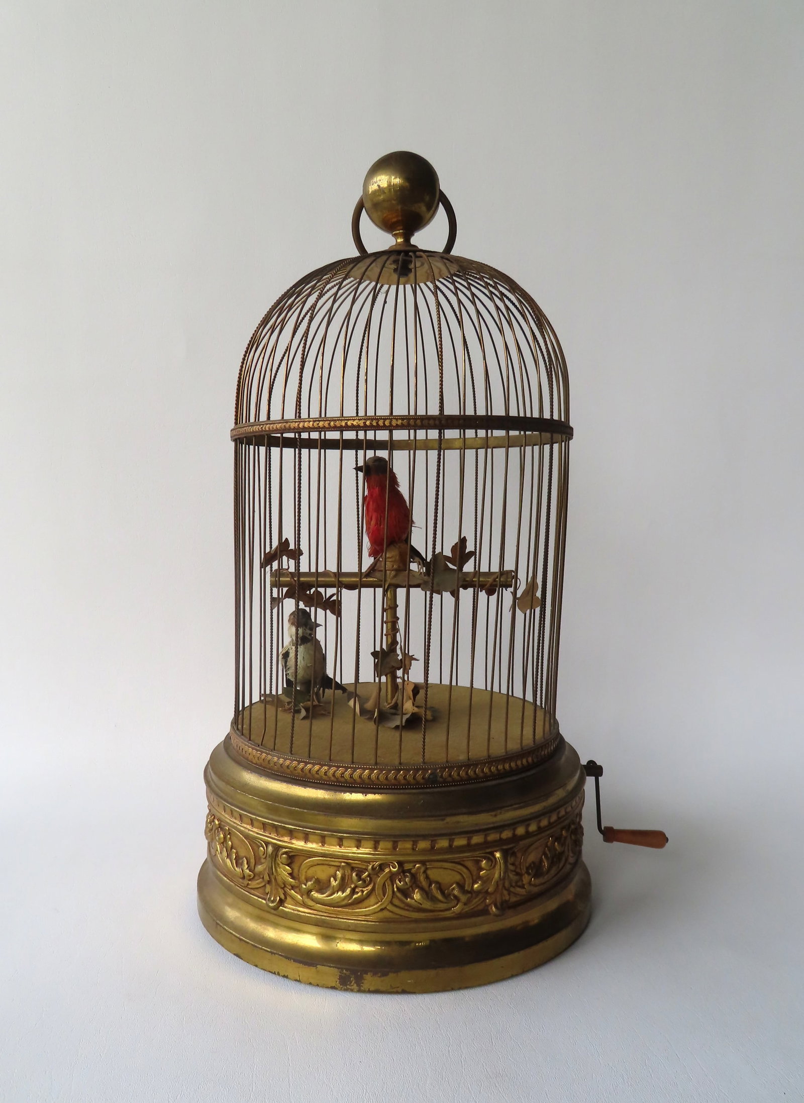 A French brass automaton bird cage with 2 singing articulated birds activated by hand crank on side.: A French brass automaton bird cage with 2 singing articulated birds activated by hand crank on side. The cage is mounted on a base decorated with embossed oval links and leaves. Signed on underside of