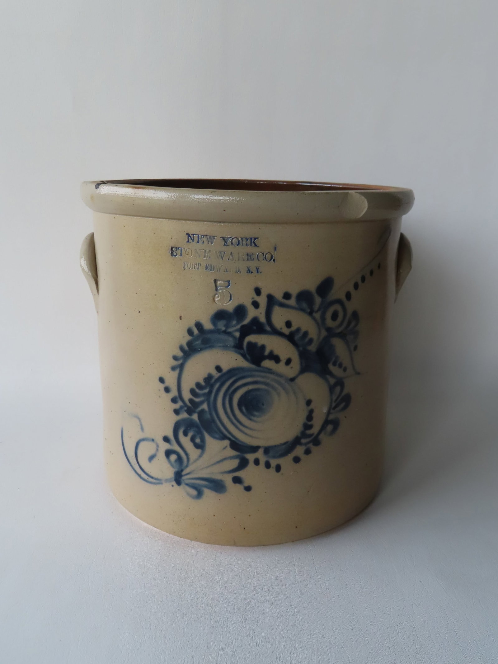 Stoneware crock, 5 gallon, decorated with a large cobalt blue flower, with the impressed mark of: Stoneware crock, 5 gallon, decorated with a large cobalt blue flower, with the impressed mark of "NEW YORK STONEWARE CO. / FORT EDWARD N.Y.", 19th century. Condition: 2 edge chips and irregular tight 