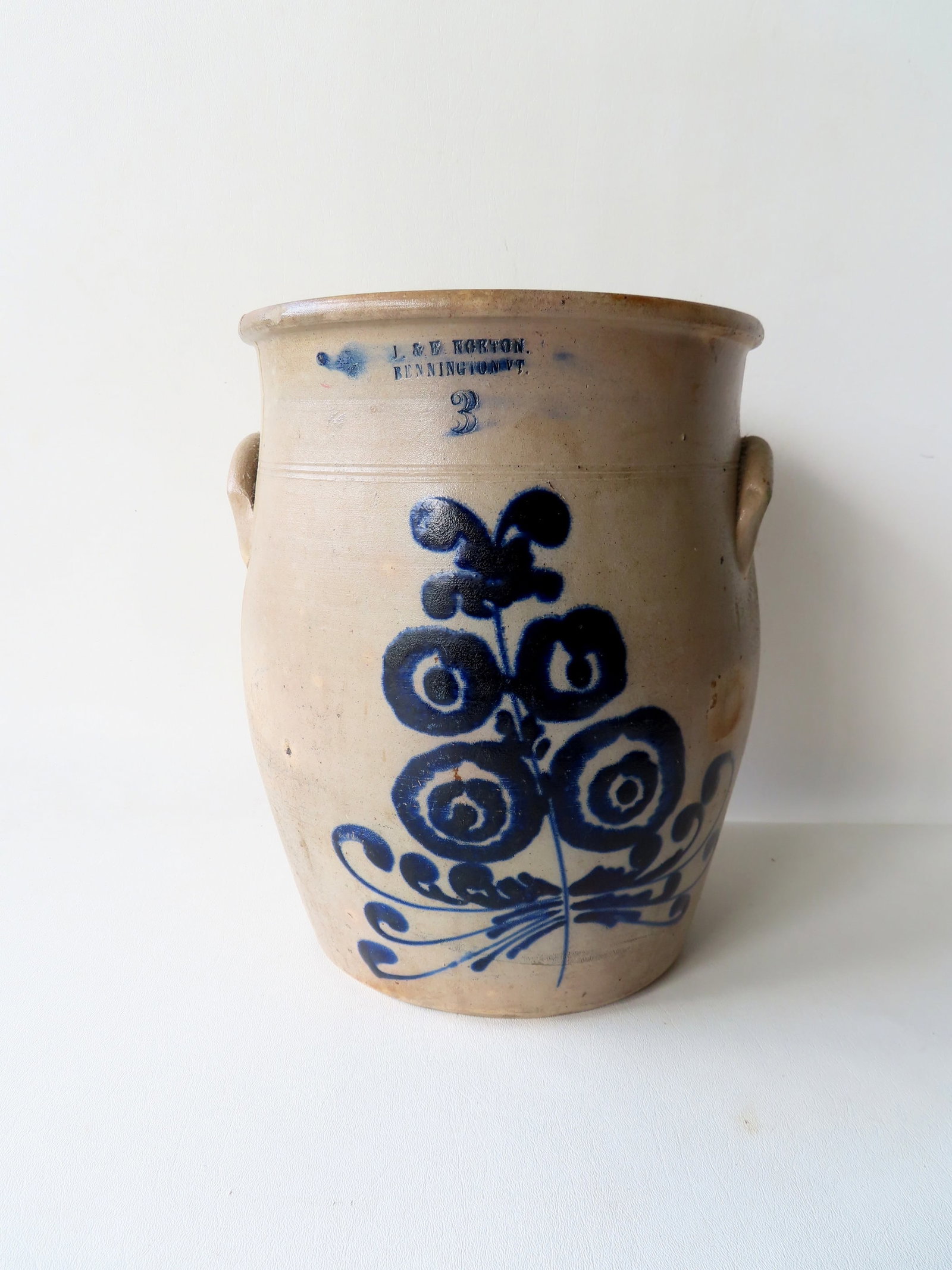 Marked "L & E NORTON. BENNINGTON VT" stoneware 3 gallon crock decorated with a large cobalt deep: Marked "L & E NORTON. BENNINGTON VT" stoneware 3 gallon crock decorated with a large cobalt deep cobalt blue flower. Three hairlines extending from rim (note 2 are connected and U-shaped surrounding e