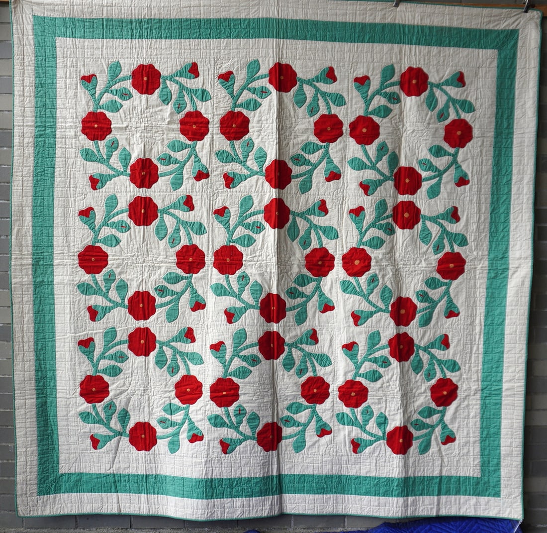 An applique quilt in Rose Wreath pattern with green and white quilted border, early 20th century.: An applique quilt in Rose Wreath pattern with green and white quilted border, early 20th century. All hand sewn in very good condition. Measures 78" x 79".