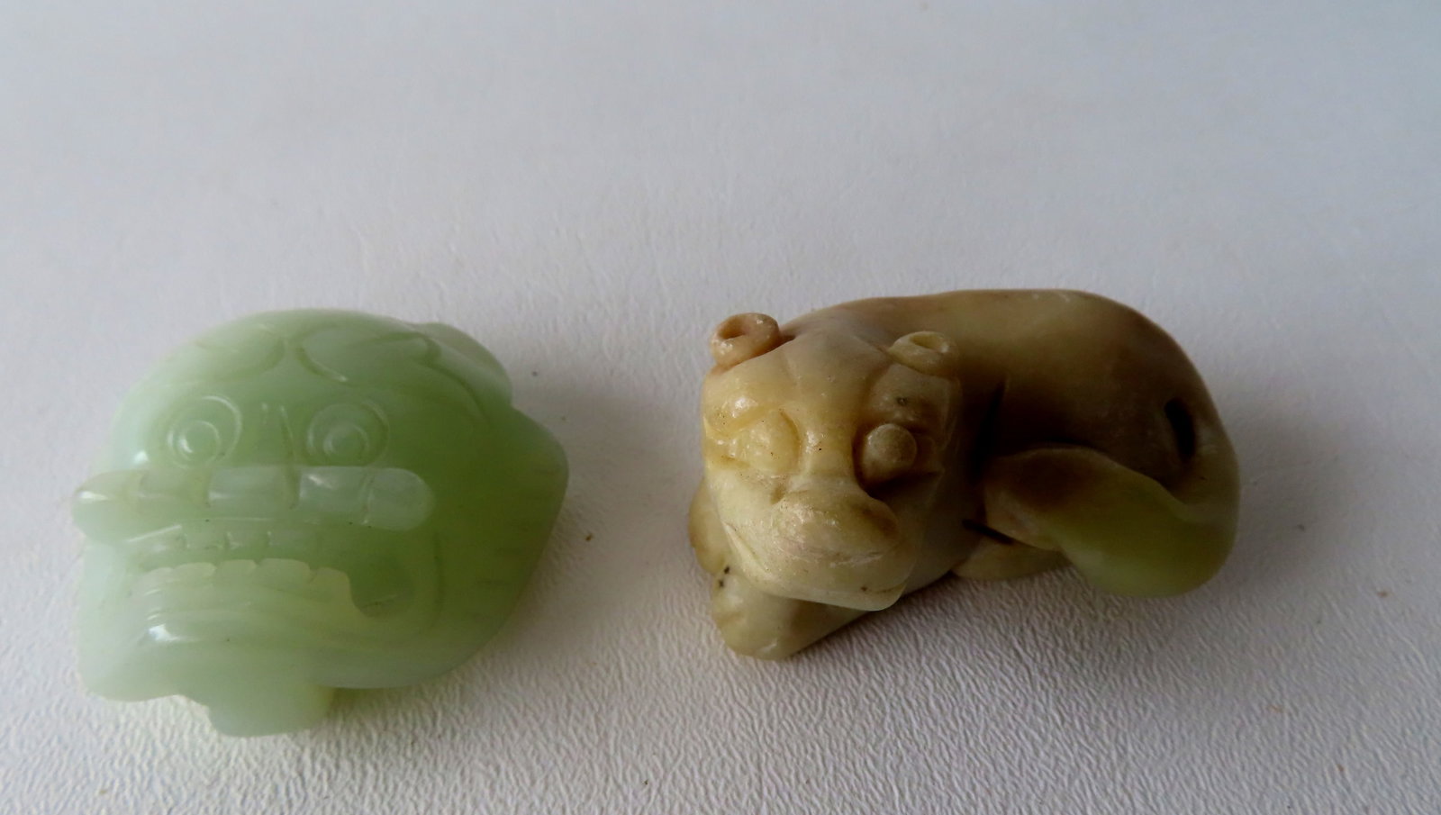 Two small oriental carved objects including a jade animal face buckle and stone resting dog: Two small oriental carved objects including a jade animal face buckle and stone resting dog ornament, both believed to be 19th century. The dog measures 2 1/2"L x 1 5/8"H. Both without damage and in v