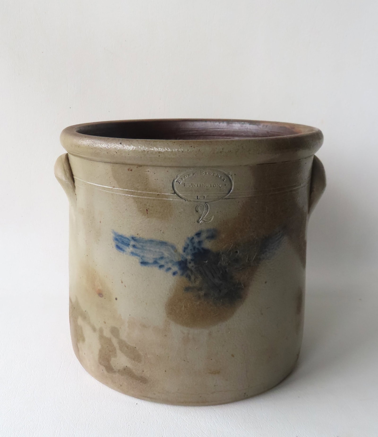 Stoneware 2 gal. crock "BROWN BROTHER / HUNTINGTON L.I.", decorated with a cobalt blue spread wing: Stoneware 2 gal. crock "BROWN BROTHER / HUNTINGTON L.I.", decorated with a cobalt blue spread wing eagle. Staining especially on the front side, hairline on the side and front extending upward from ba