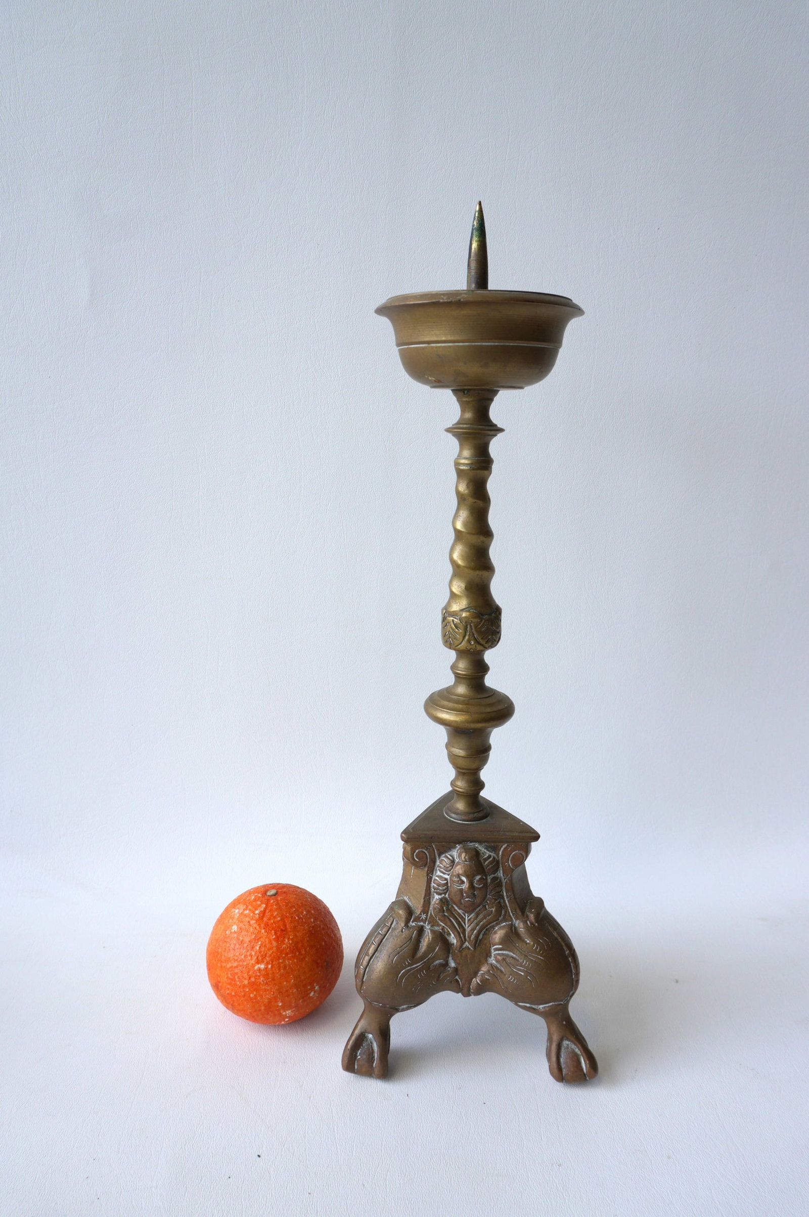 A Dutch bronze or brass pricket stick having a twisted and turned column leading to a triangular: A Dutch bronze or brass pricket stick having a twisted and turned column leading to a triangular plinth decorated with raised faces and mounted on claw and ball feet, circa 1700. Measures 16 1/2"H x 5