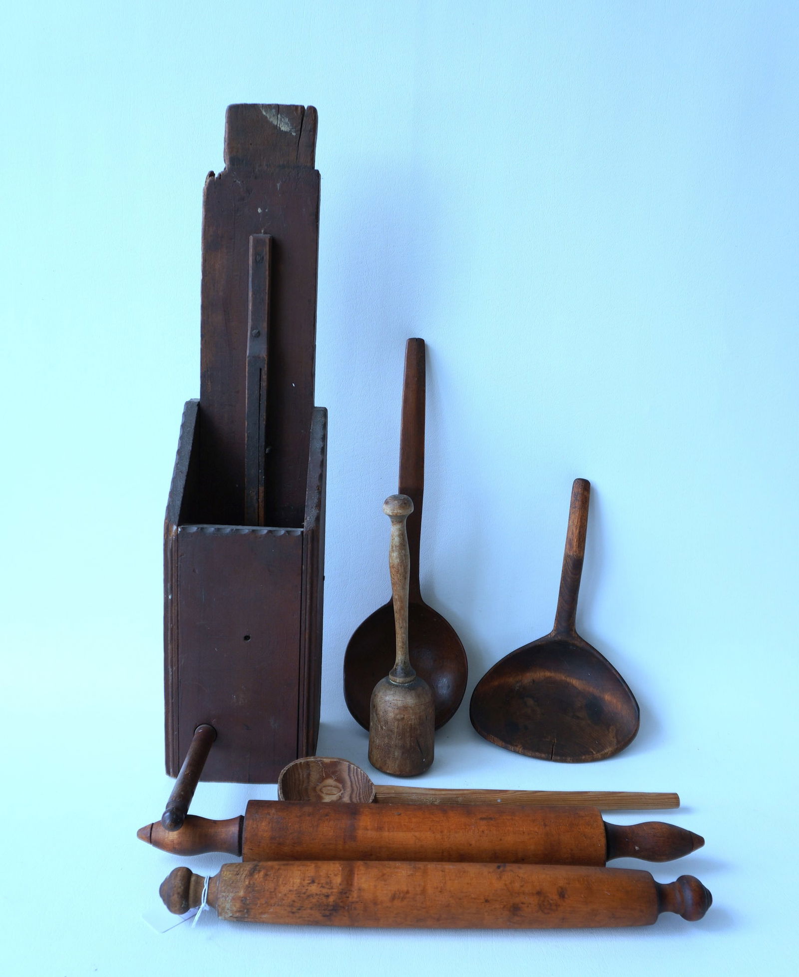 Seven pieces of hand made country treenware, 19th century, including 2 rolling pins, 3 scoops, 1: Seven pieces of hand made country treenware, 19th century, including 2 rolling pins, 3 scoops, 1 masher and 1 unusual grinding device with turned wooden handle and wooden gears in original red stain,