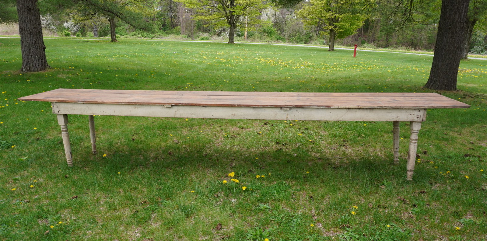 Very large farm table with 3 board scrubbed pine top, wrap around apron, and turned legs in white: Very large farm table with 3 board scrubbed pine top, wrap around apron, and turned legs in white paint. One of the legs near matching so likely a replacement - table wobbles slightly so the base need
