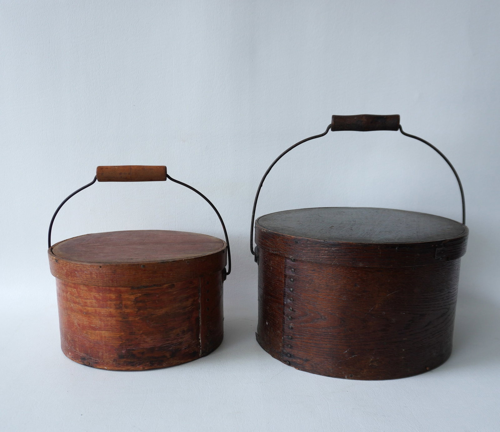 Two pantry boxes with bale handles, 19th century, one with traces of original red paint. The largest: Two pantry boxes with bale handles, 19th century, one with traces of original red paint. The largest measures 11" diameter x 61 1/w2"H. Both in good condition. Provenance: From the Carole Ostergren co