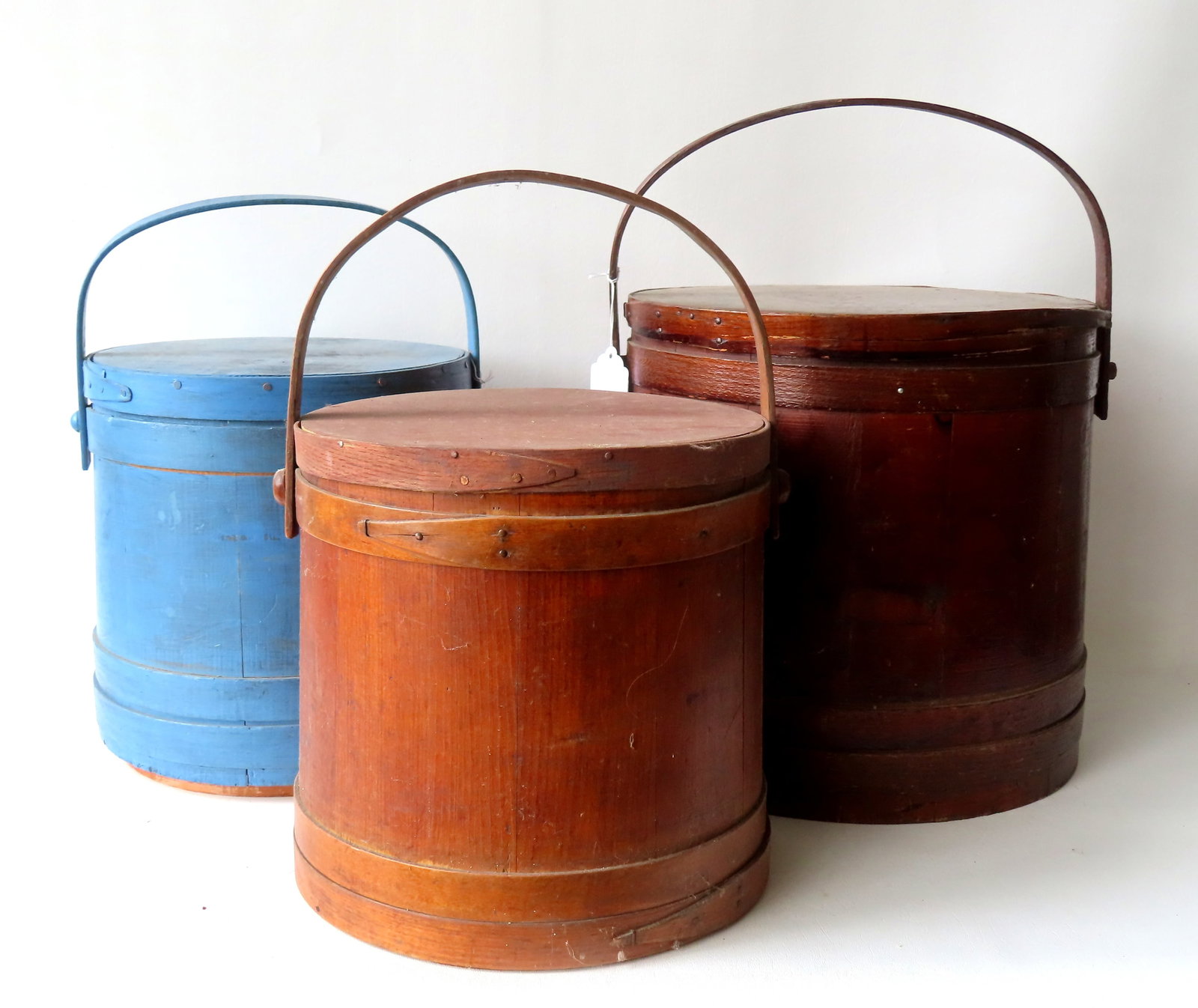 Three large firkins, late 19th to early 20th century. The largest in old natural finish - loss to: Three large firkins, late 19th to early 20th century. The largest in old natural finish - loss to wrapped edge of lid, else good condition - 15 1/4" diameter x 14 1/2"H; the next in a newer blue paint