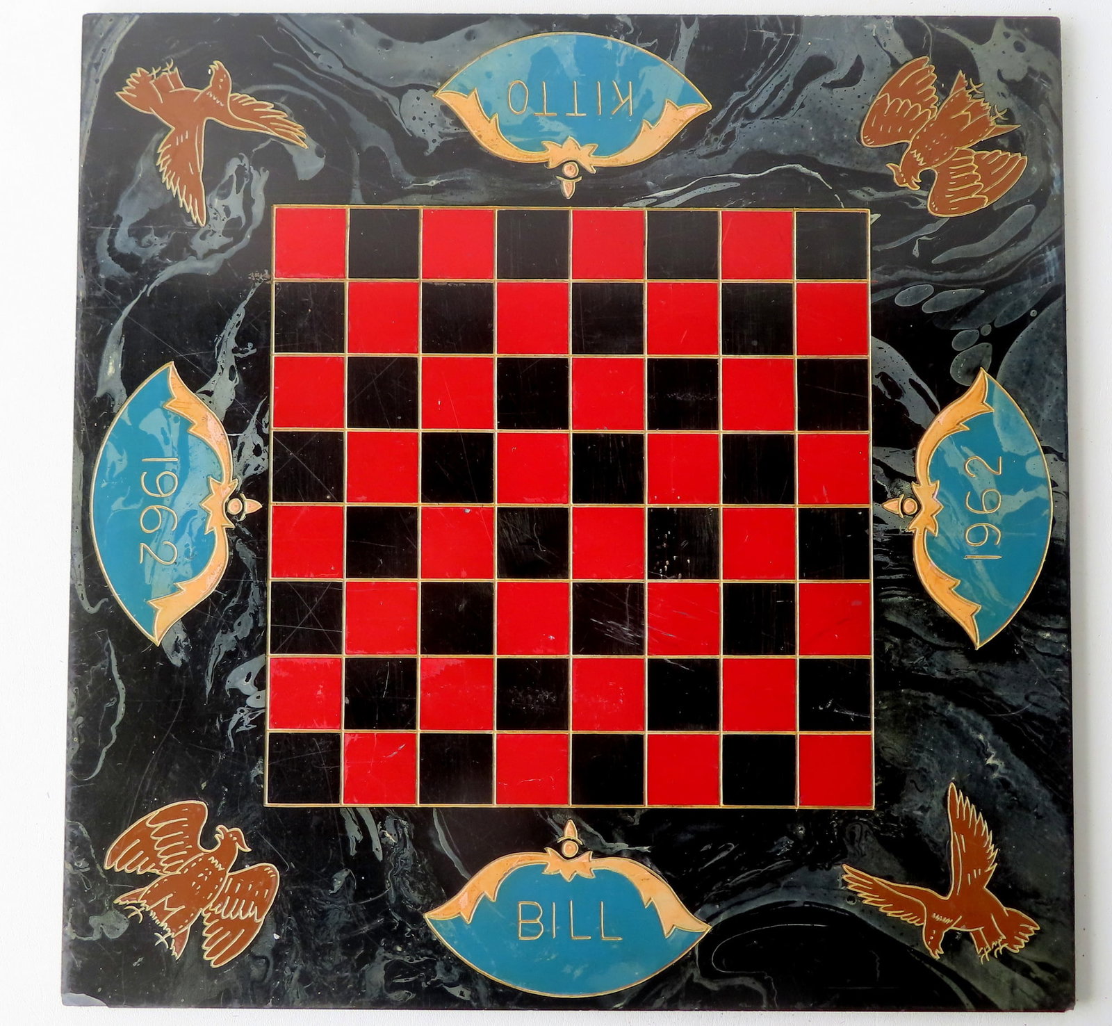 A good polychrome slate game board with red and black squares: A good polychrome slate game board with red and black squares surrounded by a marbleized border with incised spread wing eagles in the corners, incised date "1962" on 2 sides and the names of players 