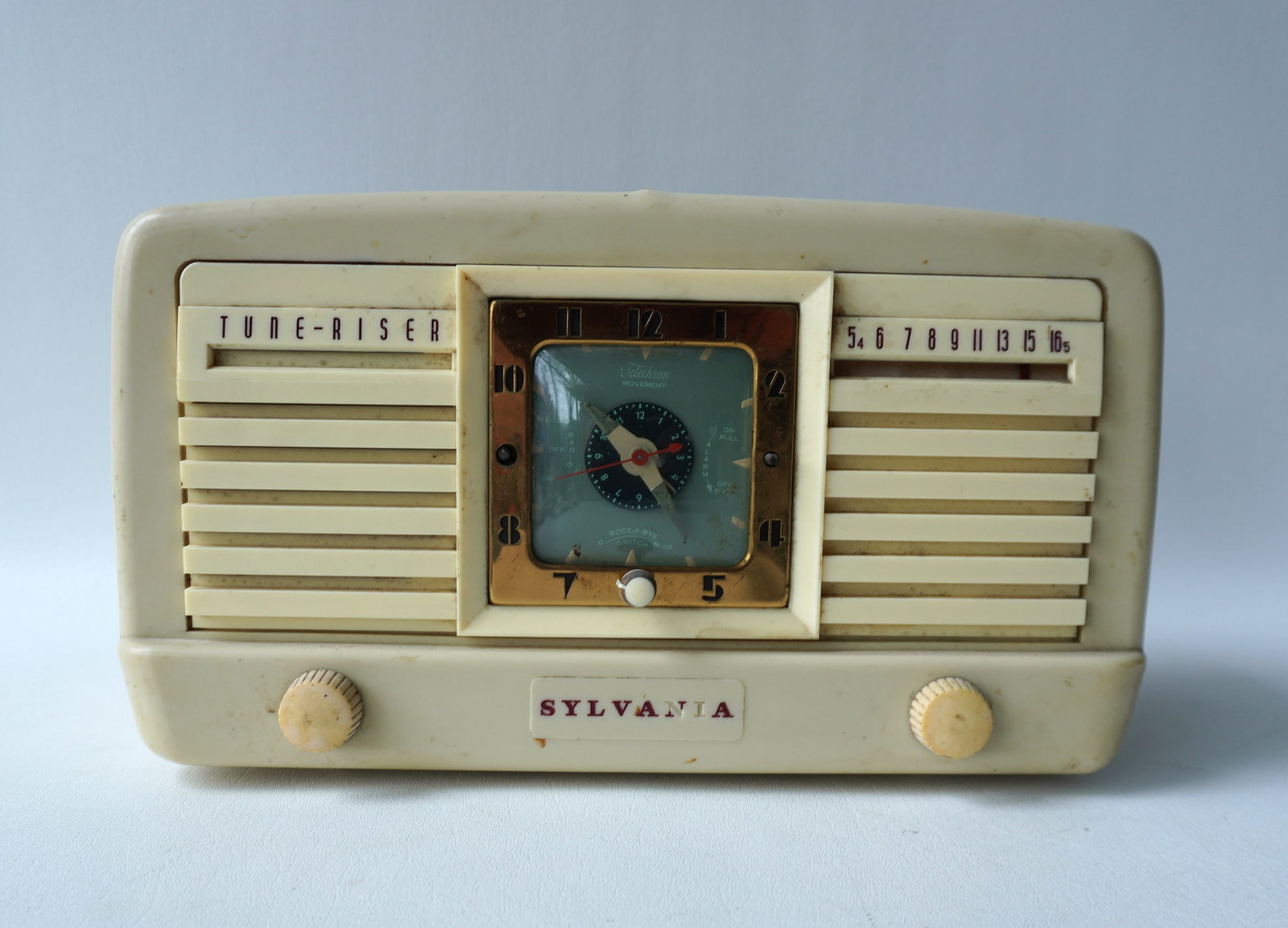 Sylvania Tune-Riser white plastic clock radio: Sylvania Tune-Riser white plastic clock radio with Roc-a-Bye switch - plug in wire has been cutoff so radio cannot be tested - missing 2 adjustment knobs on front - sold as non-working. Measures 12 1/
