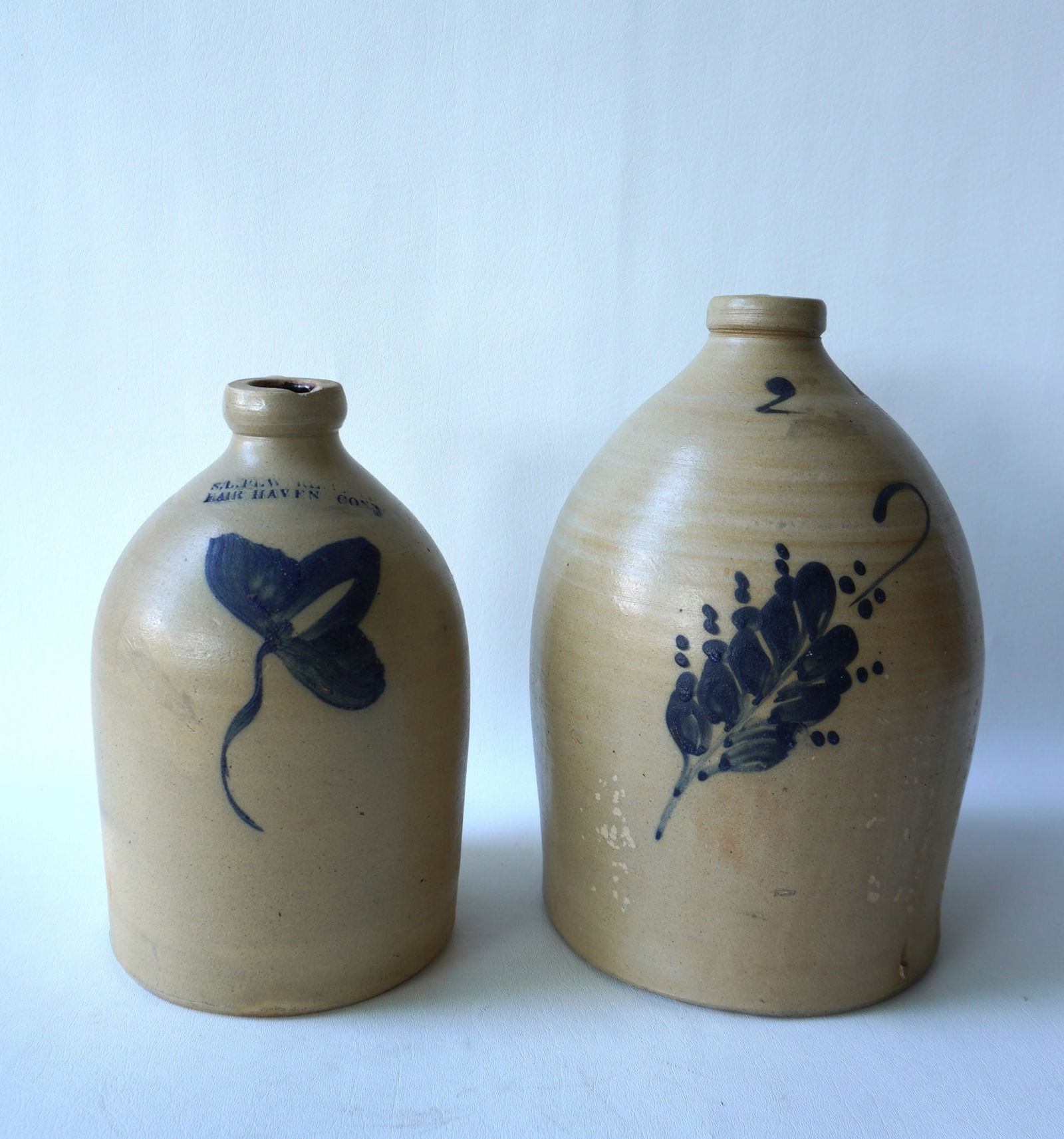 Two stoneware jugs including: Jug, 1 gallon, decorated with a cobalt blue flower, with the impressed (1 of 6)