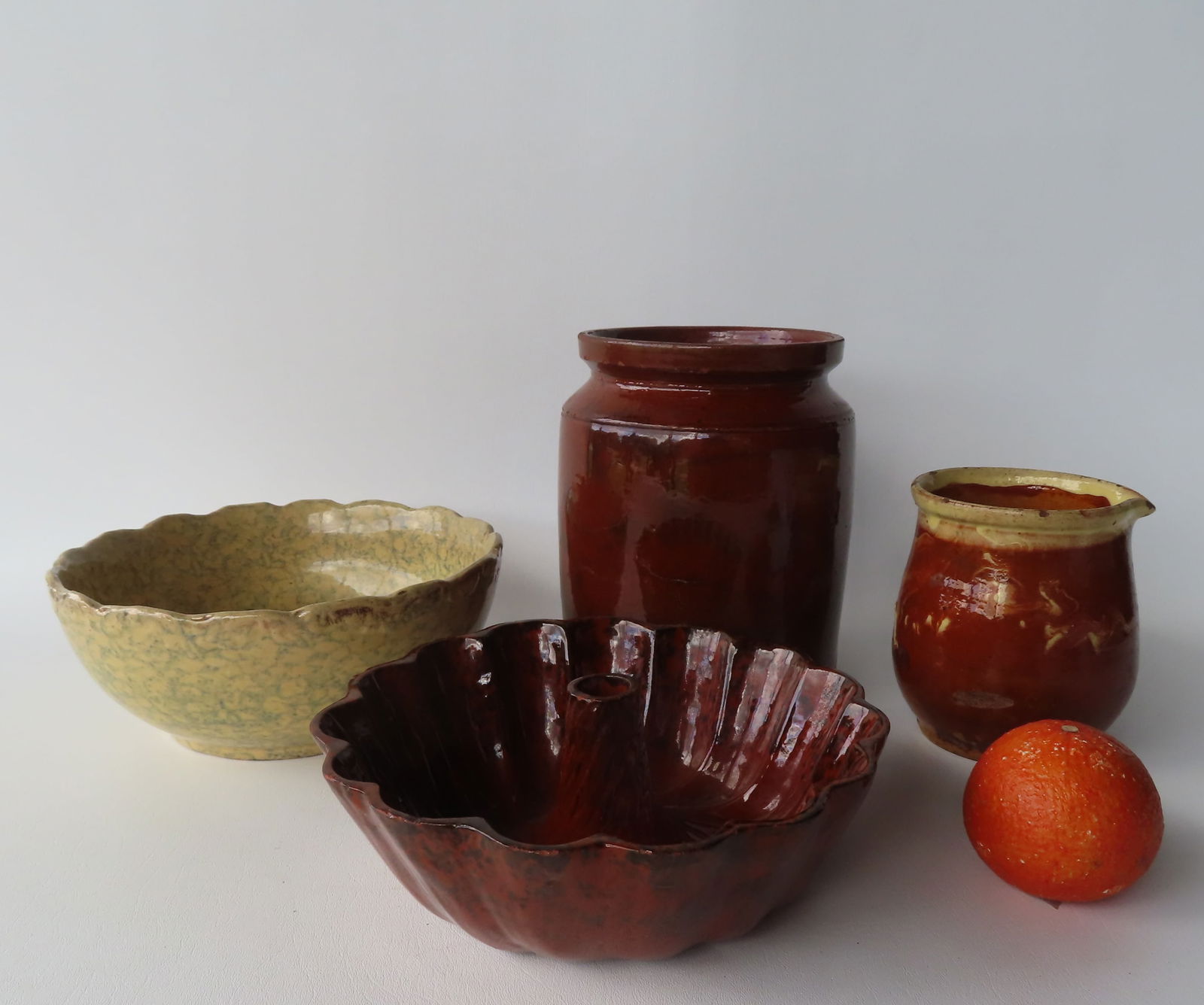 Grouping of redware and other country pottery collectibles including: A cylindrical redware jar with (1 of 15)