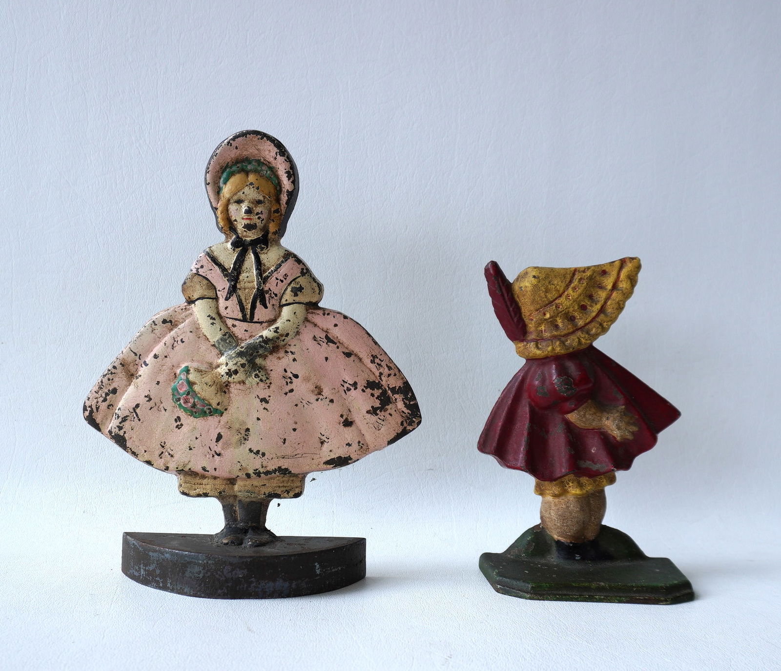 Two cast iron door stops in original paint including Sunbonnet Baby #72, and young girl holding (1 of 4)