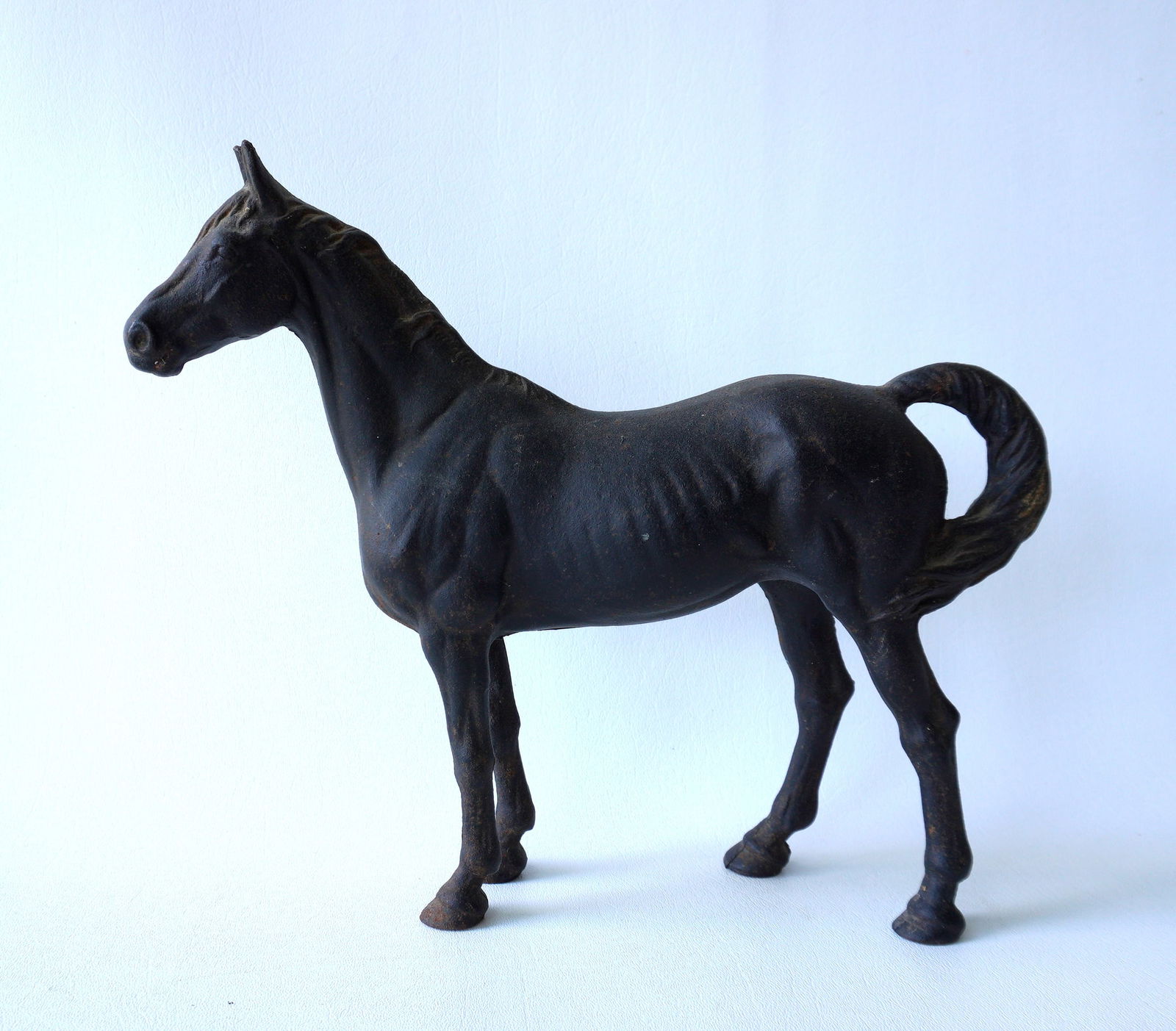 Cast iron door stop in the form of a standing horse in original black paint - some use wear to: Cast iron door stop in the form of a standing horse in original black paint - some use wear to paint, but overall good condition - measures 12"L x 11"H; together with a painted white metal horse with