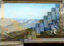 O/C Mountain landscape with figure by tents near base of mountains, some snow covered in background.