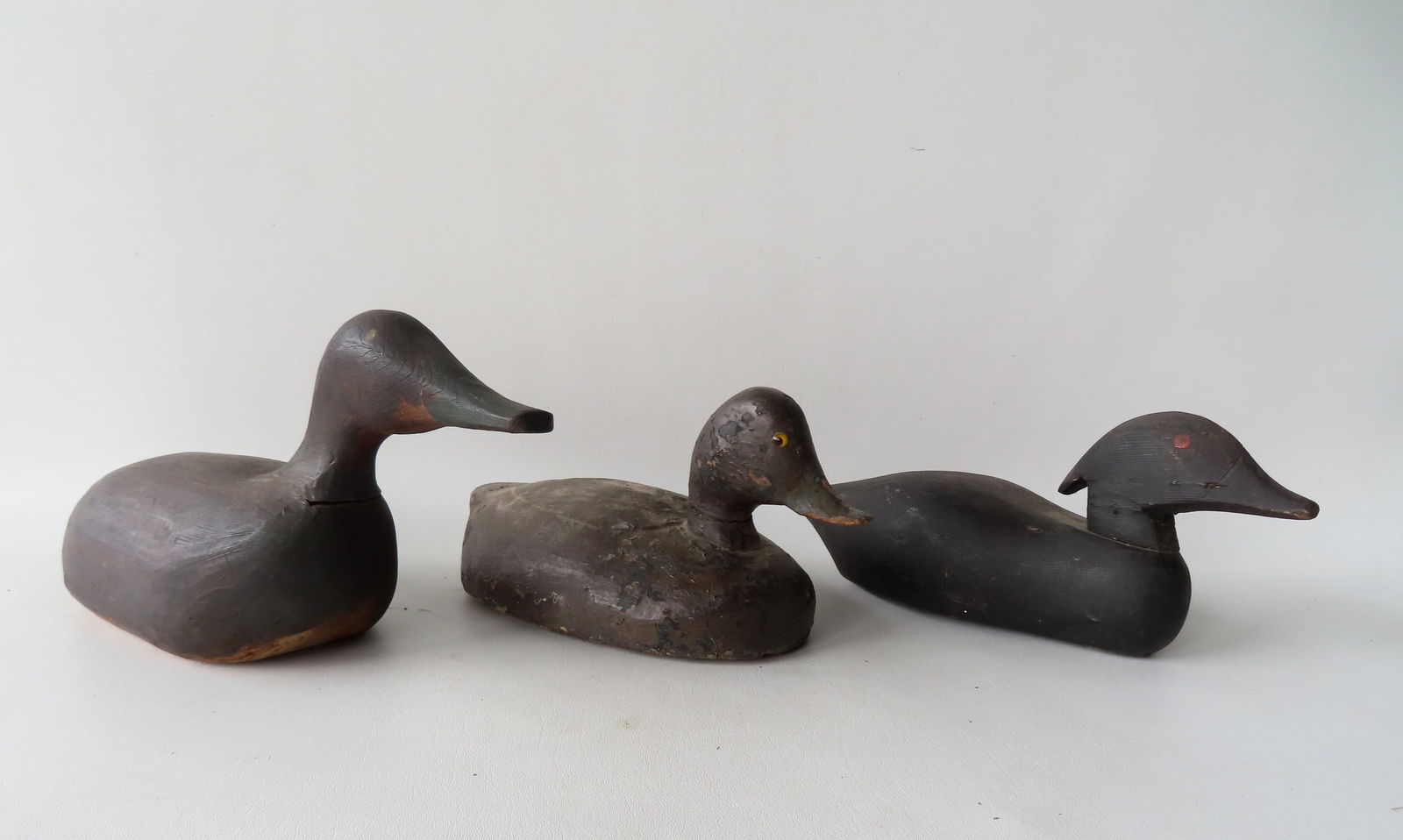 Three primitive wooden decoys, late 19th to early 20th century. Includes a swimming decoy with inset (1 of 14)