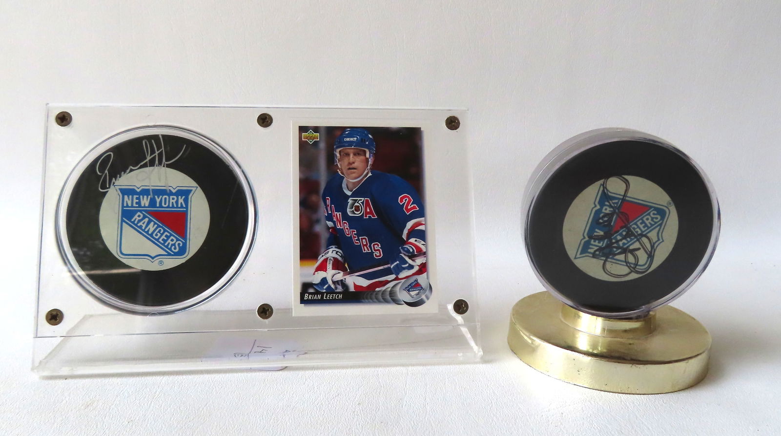 Two autographed NY Rangers hockey pucks. The first signed Brian Leetch together with his #284 1992 (1 of 8)