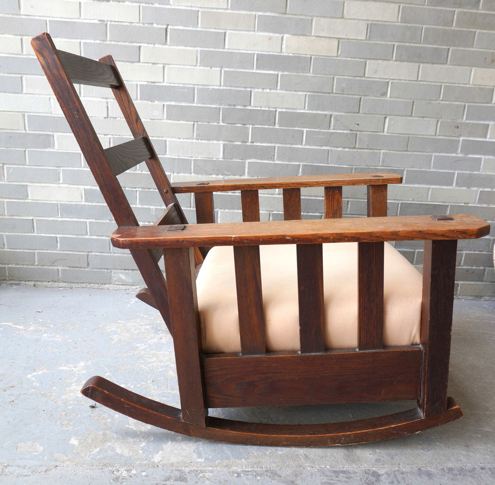 A Mission oak rocking chair with slats under arms, exposed tenon through arms, signed: A Mission oak fixed back rocking chair with slats under arms, exposed tenon through arms, signed "Hubbard, Eldridge & Miller / Rochester NY" - newer fabric covering its original seat and back cushion