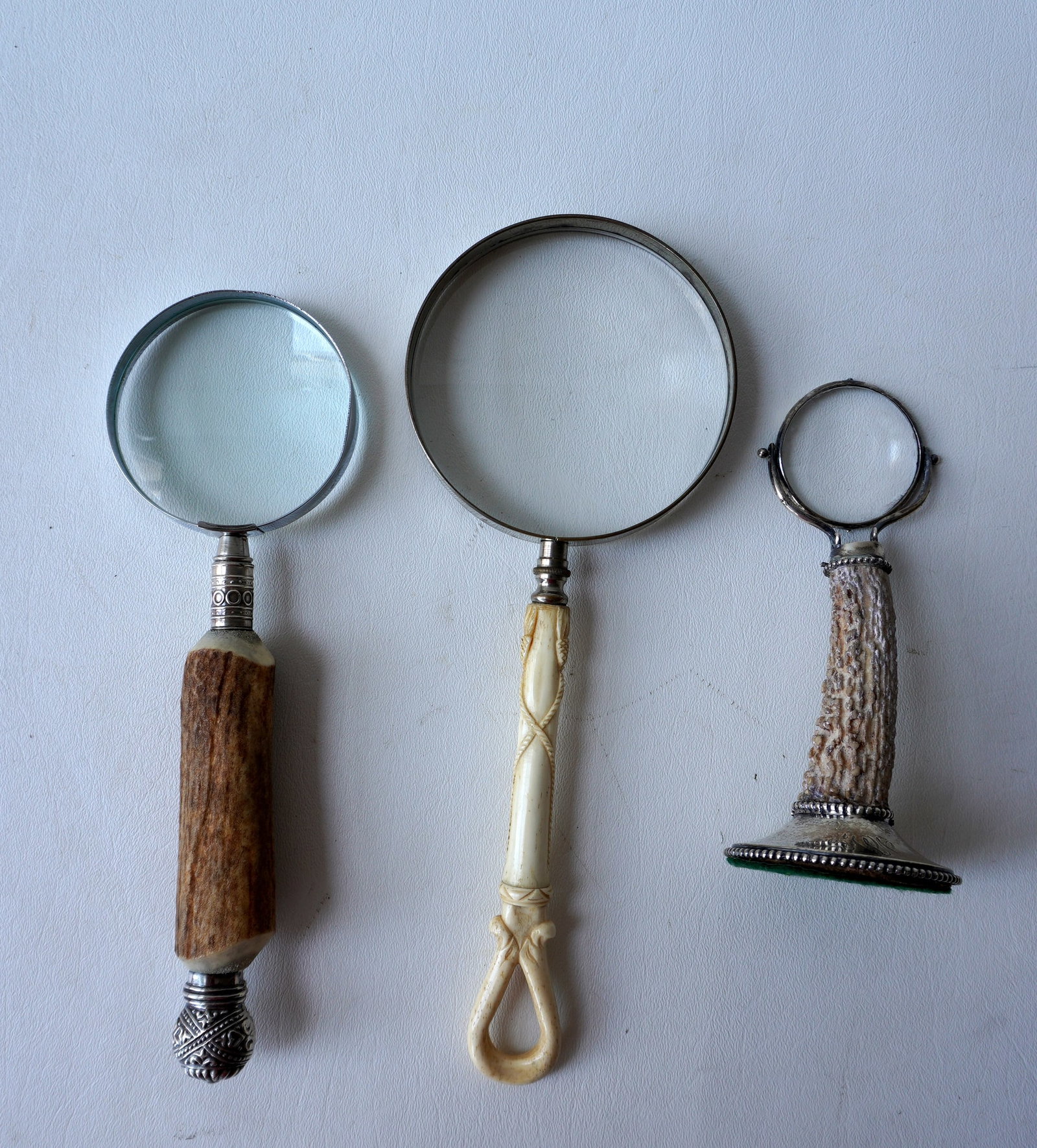 Three vintage magnifying glasses in animal horn &bone, including: Magnifier is attached to a antler: Three vintage magnifying glasses in animal horn &bone, including: Magnifier is attached to a antler horn and mounted on a sterling base - good condition - 6"H; the next with a carved bone handle decor