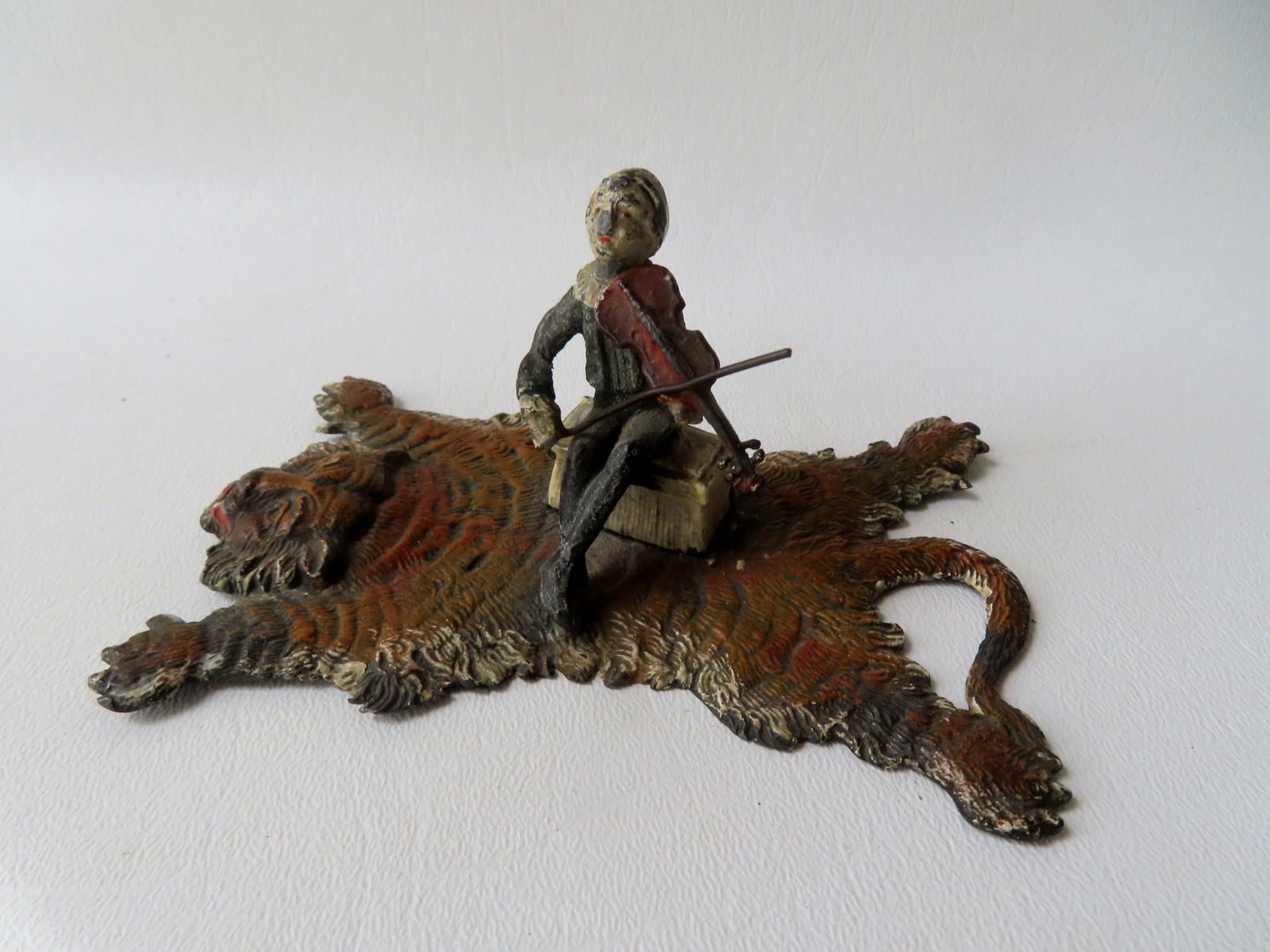 Hand painted small metal sculpture, possibly zinc, depicting a court jester playing violin seated on (1 of 7)